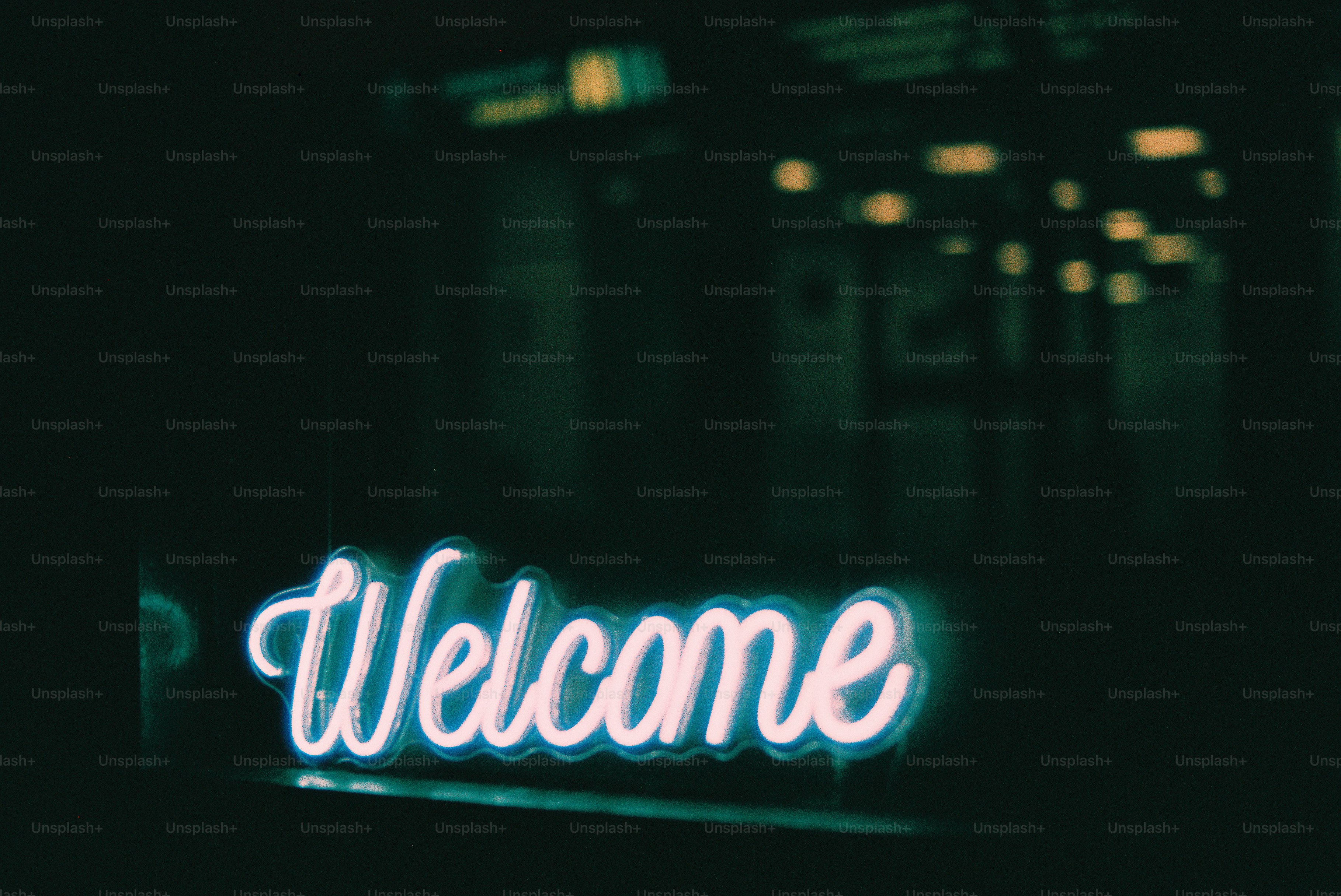 A neon sign that says "welcome" glows at night.