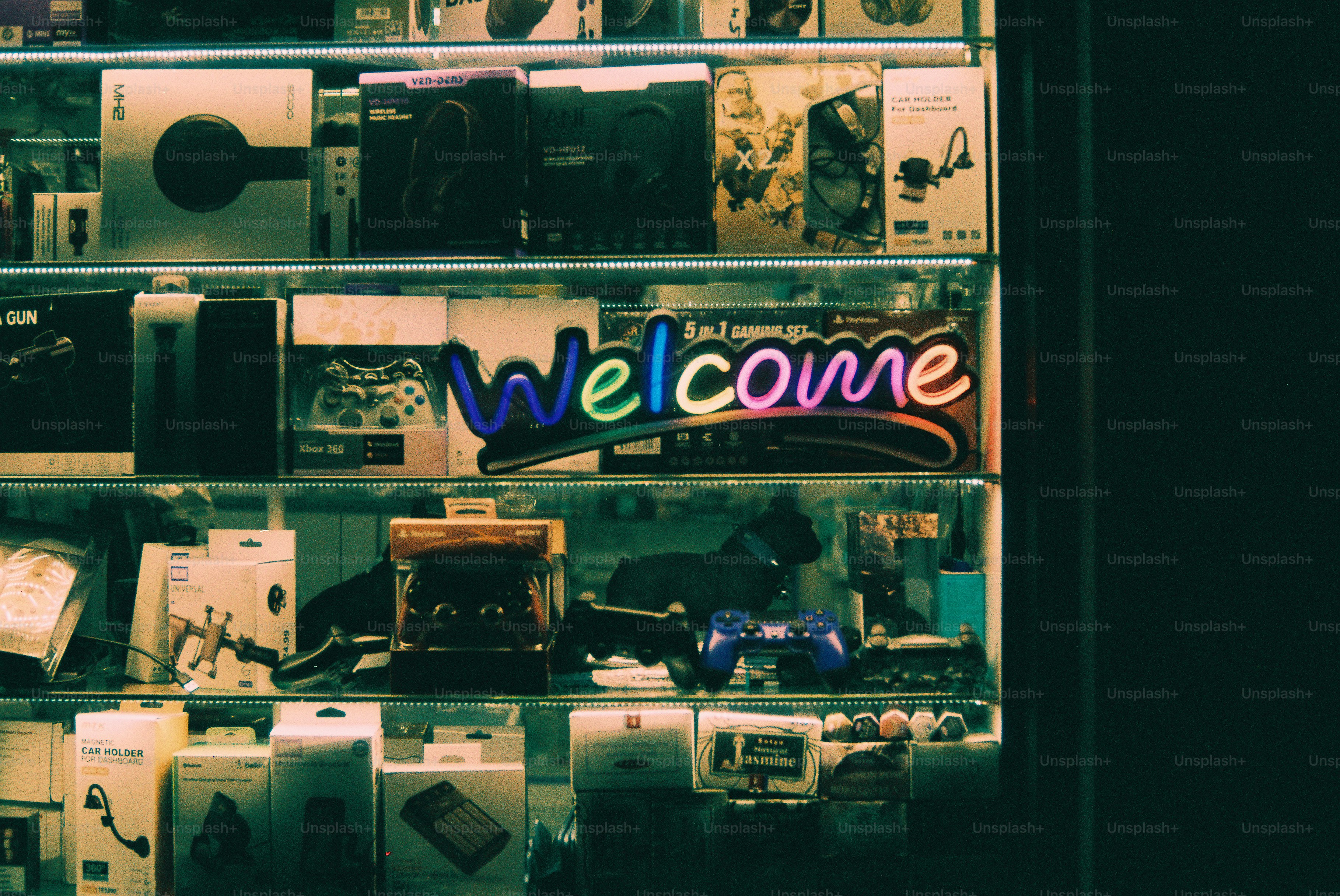 Neon welcome sign above shelves of electronics