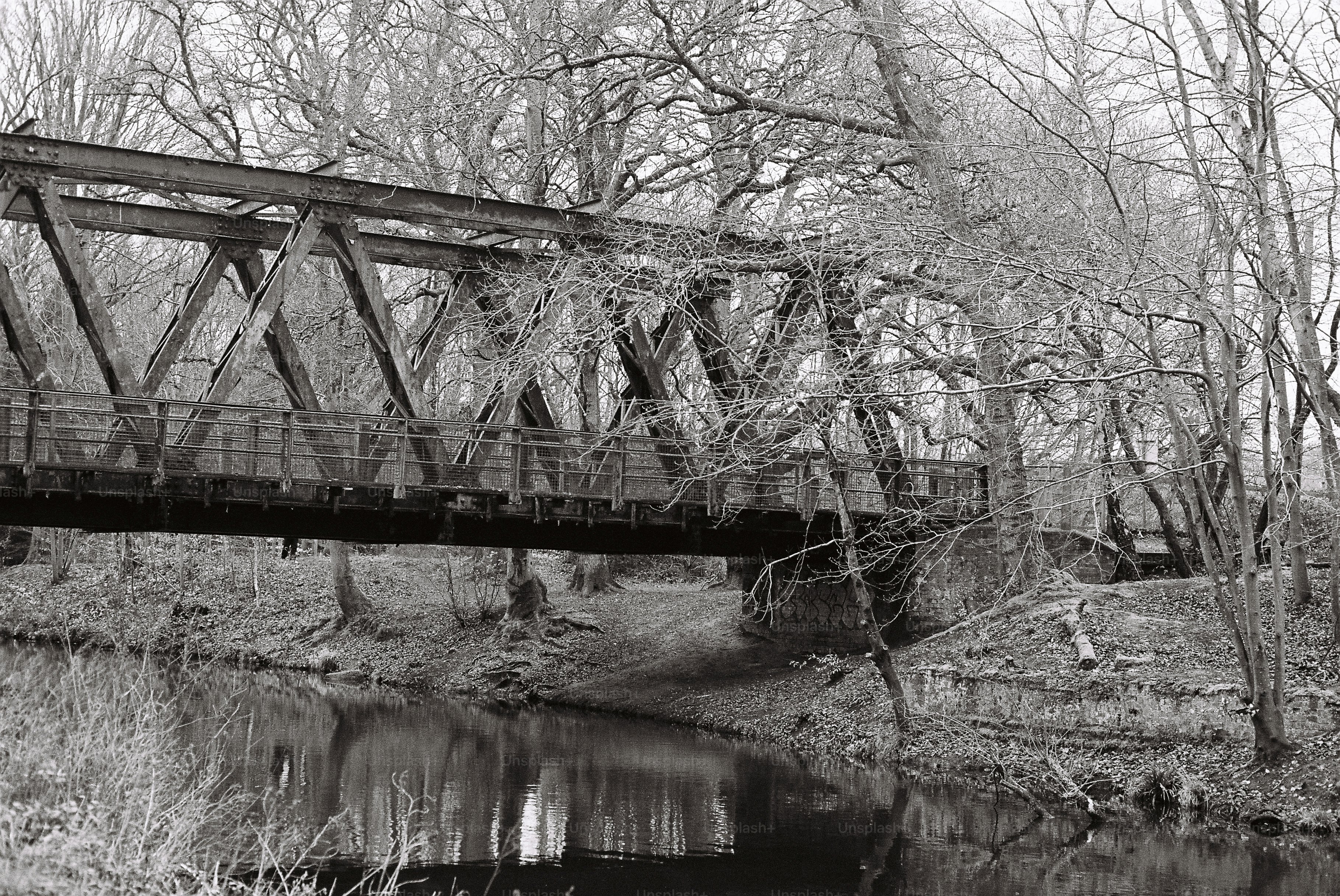A metal truss bridge crosses a calm river.