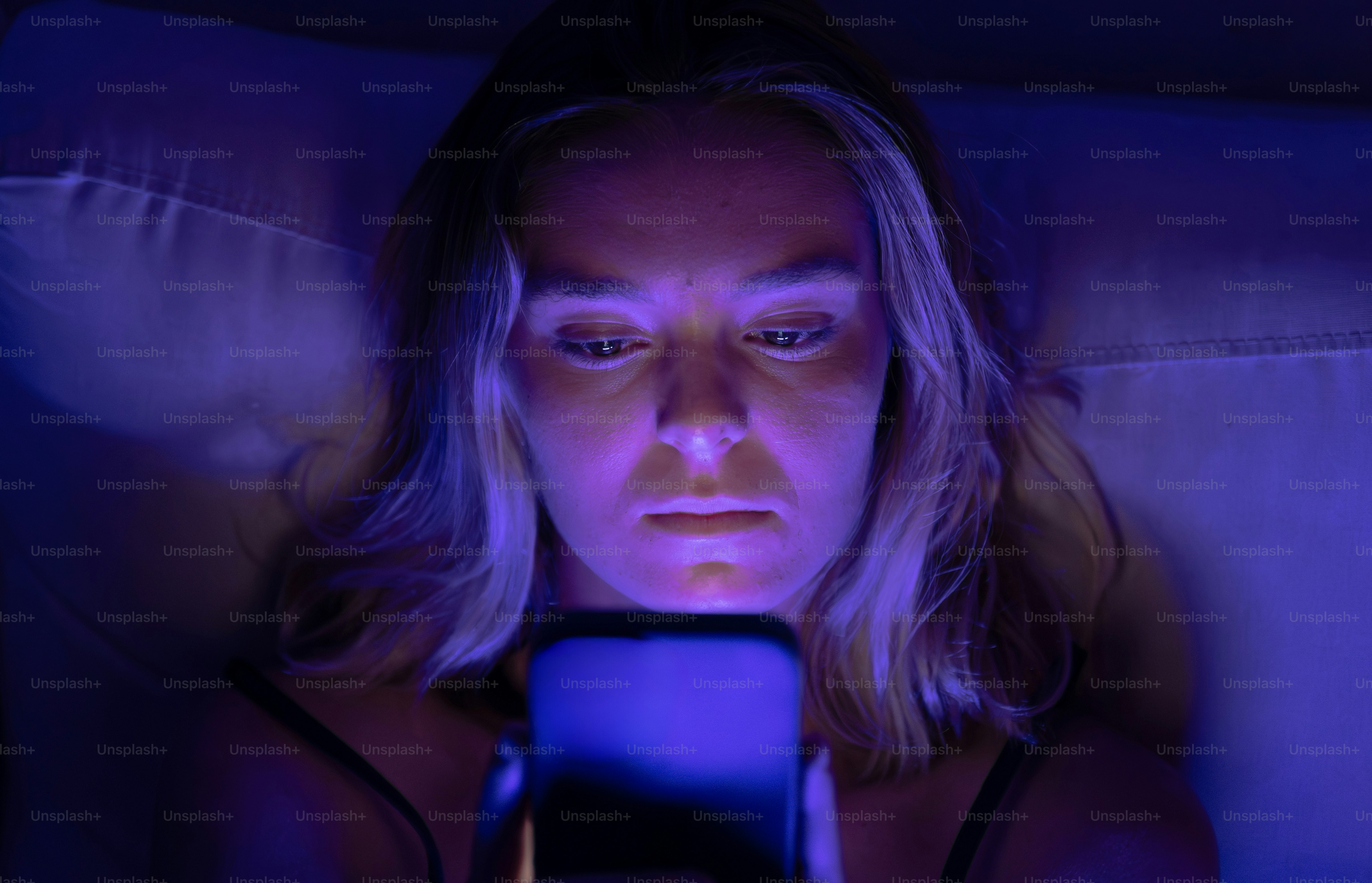 Woman illuminated by phone screen in dark room