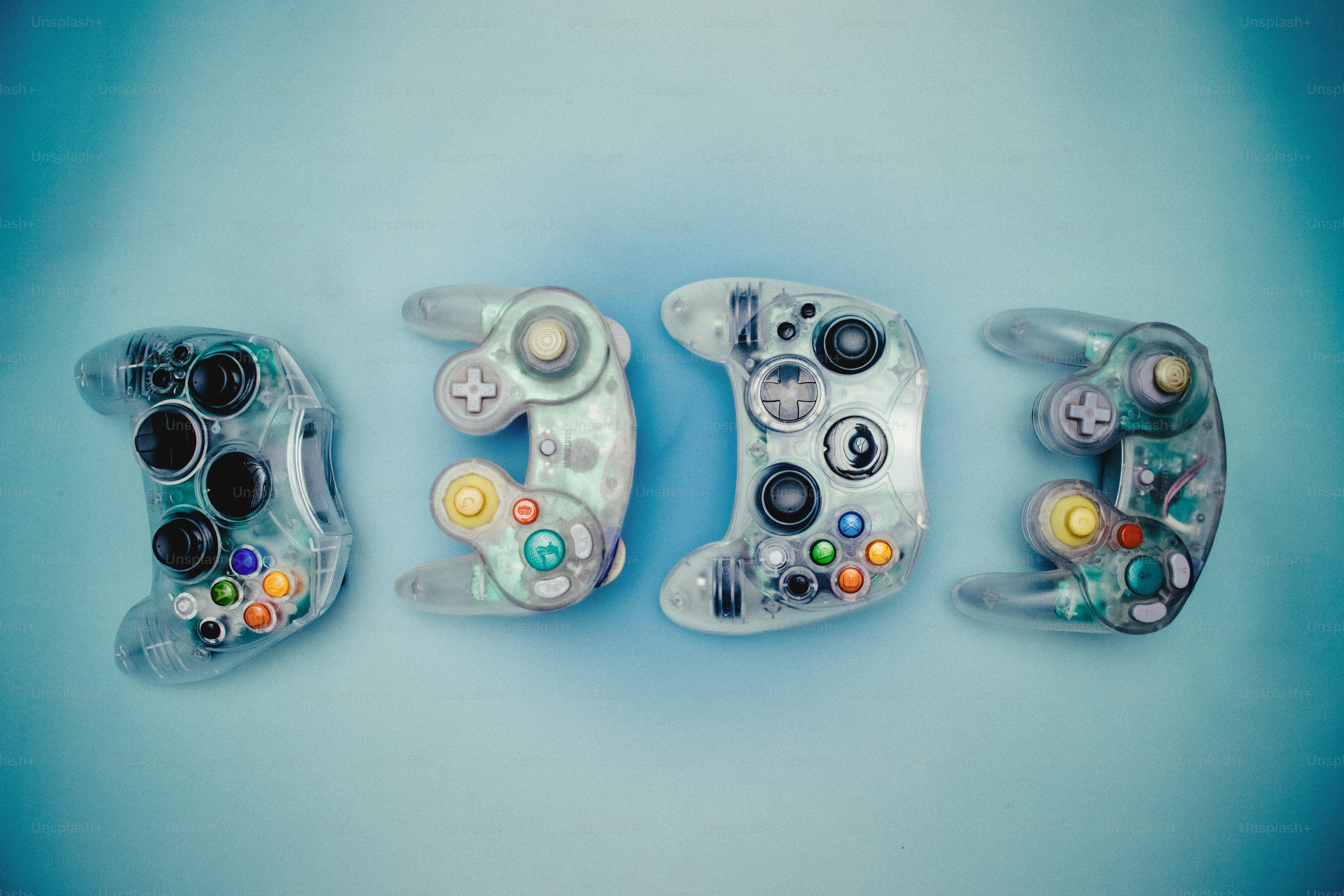 Quatre manettes de jeu vidéo transparentes sur fond bleu