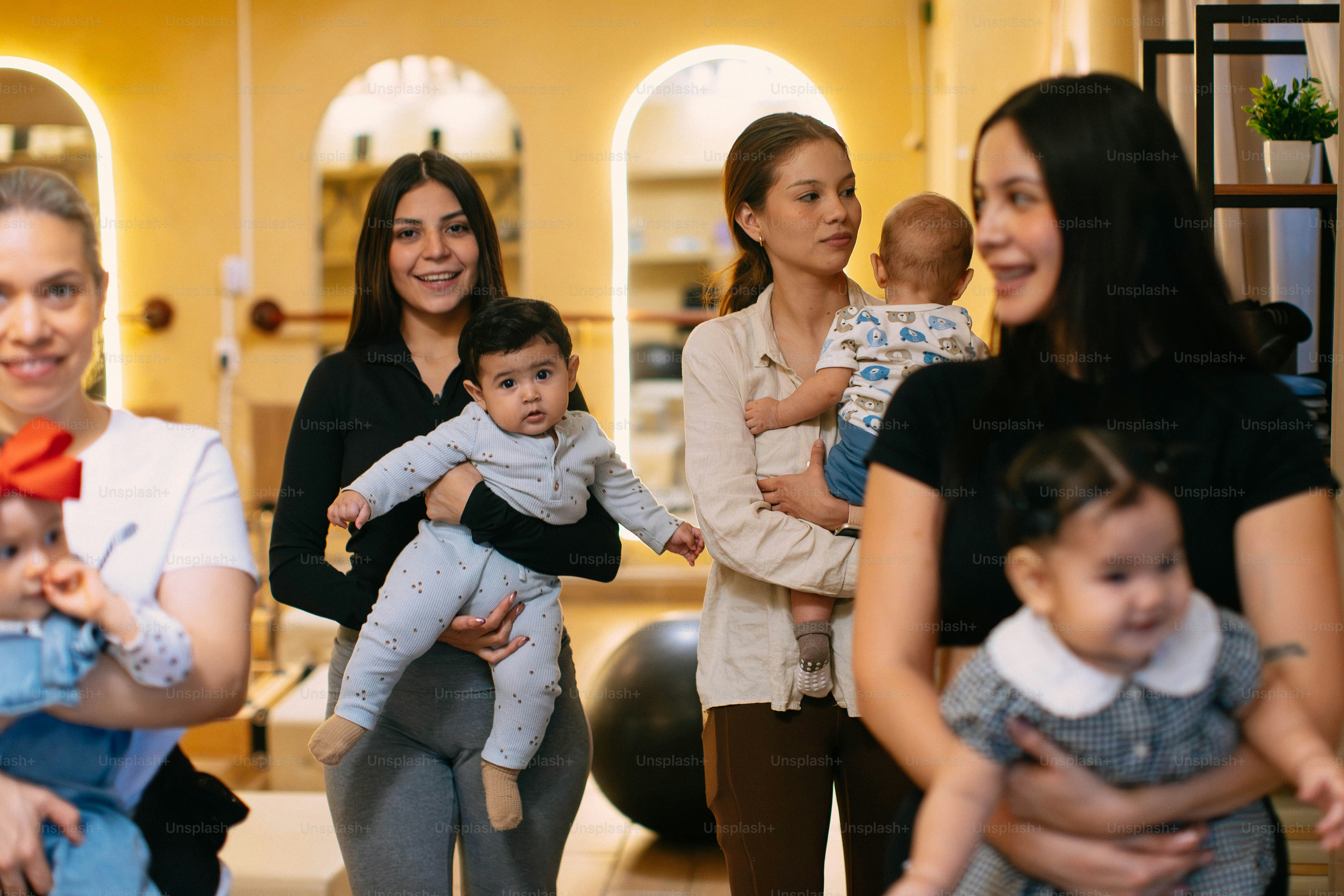 Madres sosteniendo a sus bebés en una habitación luminosa