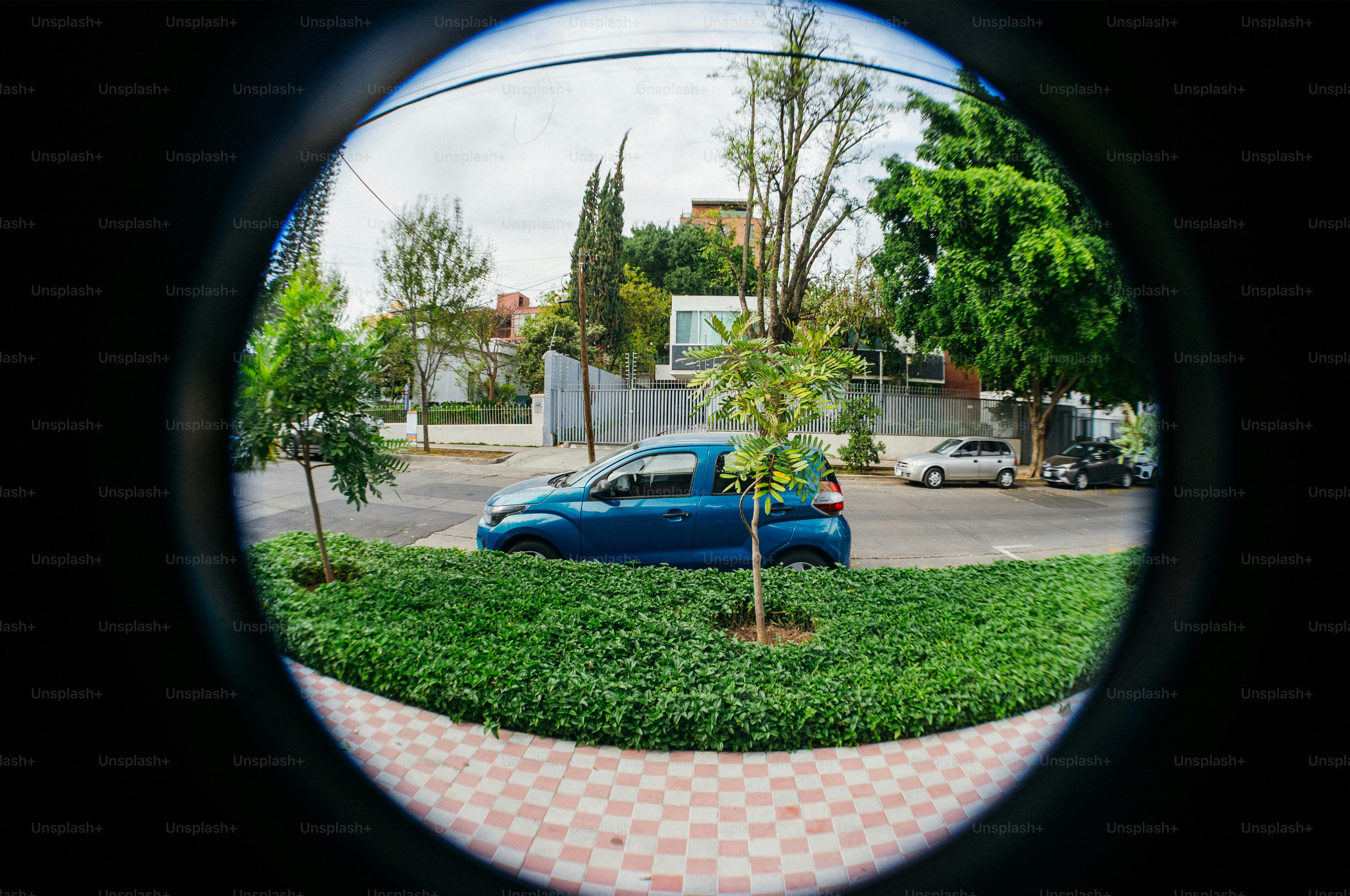 Blue car driving on a street with trees and buildings.
