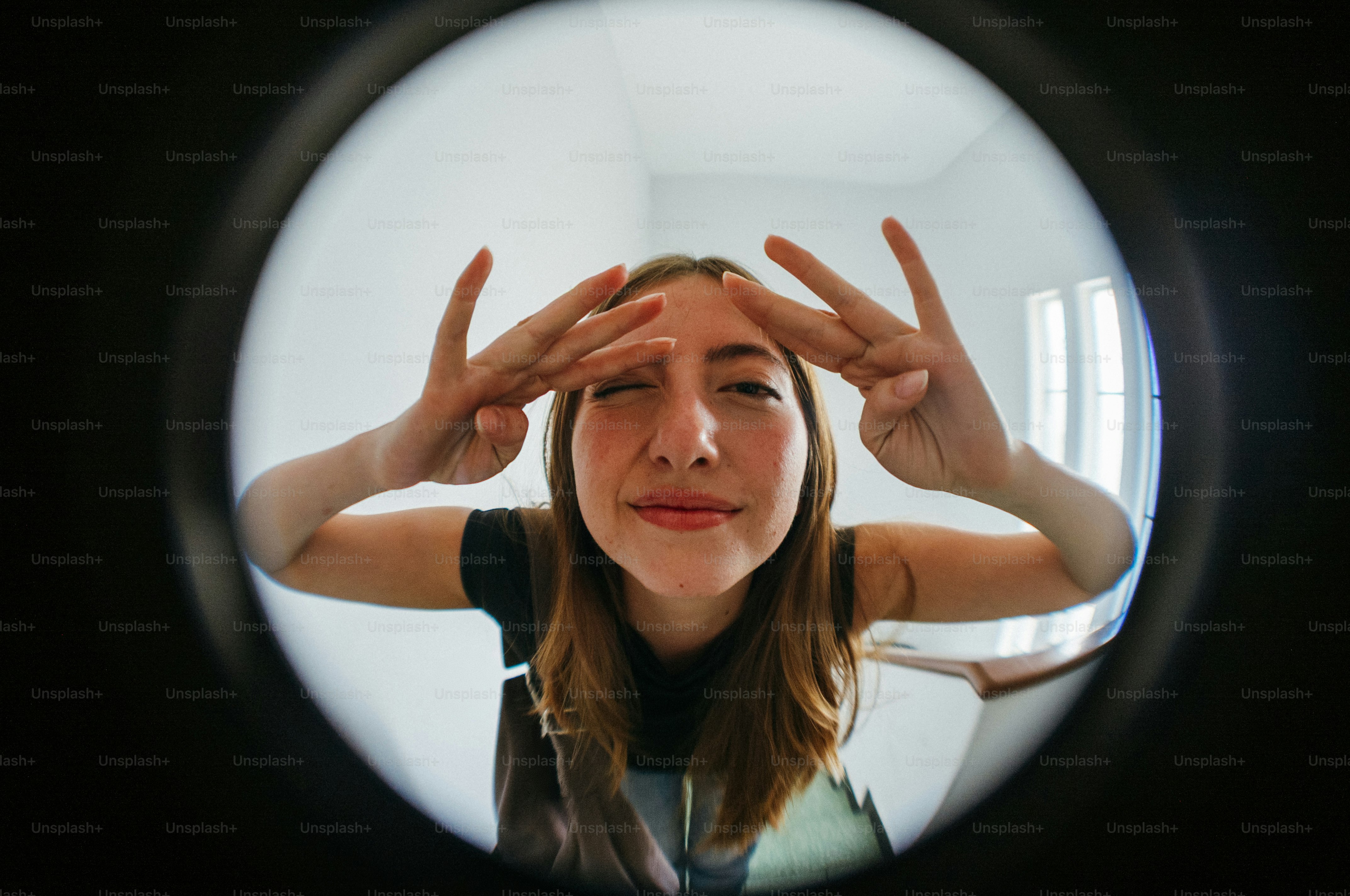 Woman making peace signs through a peephole