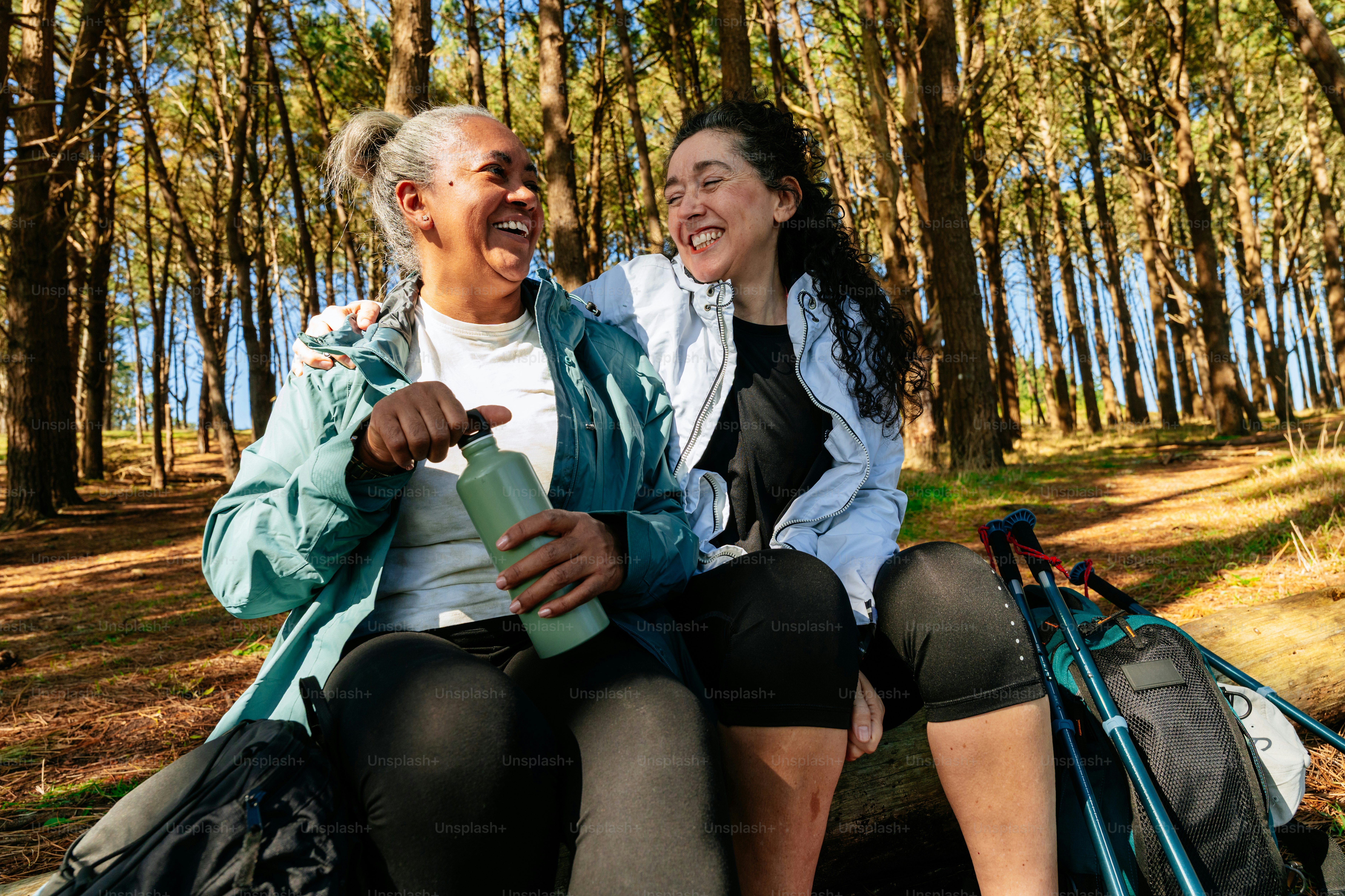 Two women laughing while hiking in a forest. photo – Forest Image on ...
