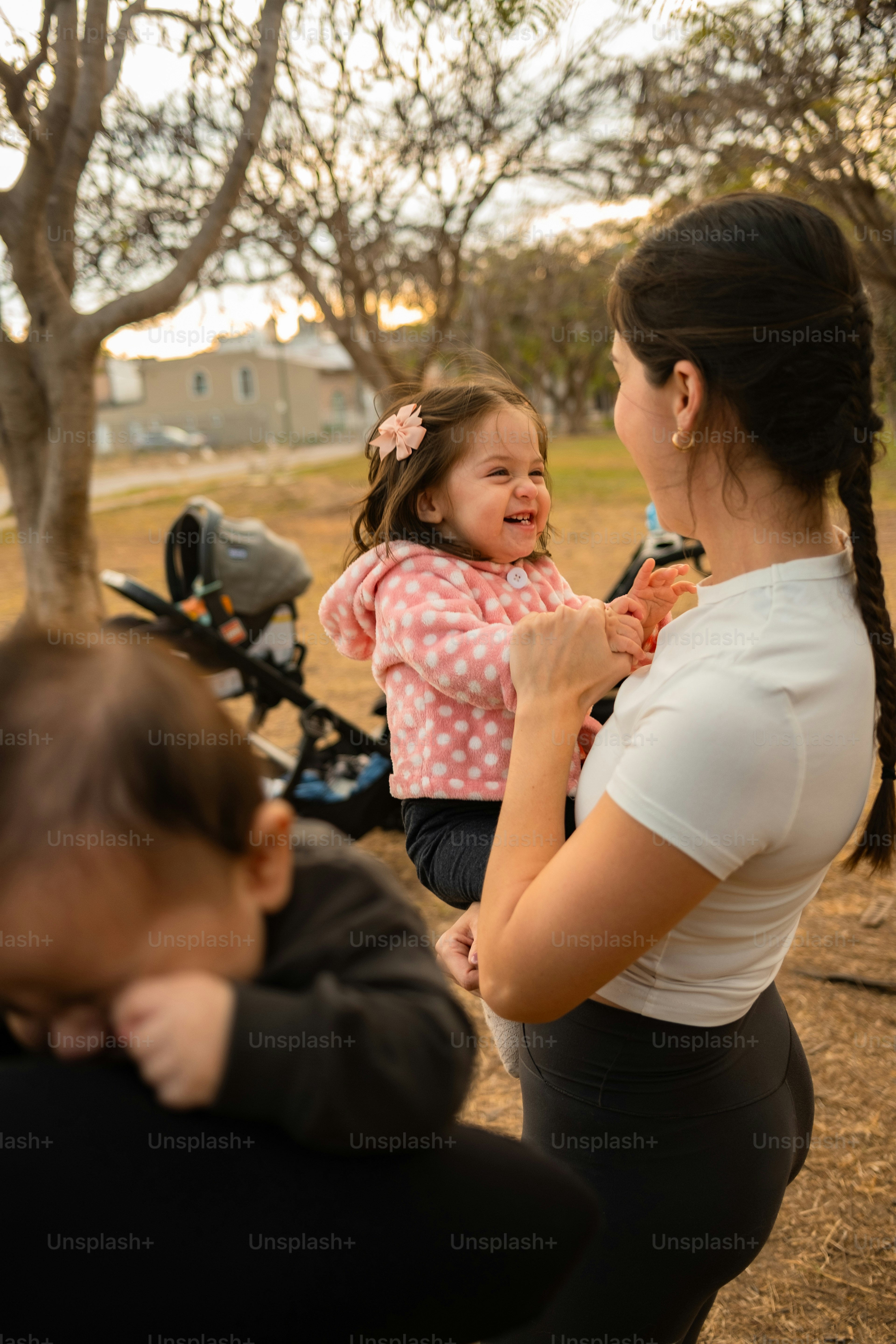 Ibu menggendong bayi perempuan yang tertawa di taman
