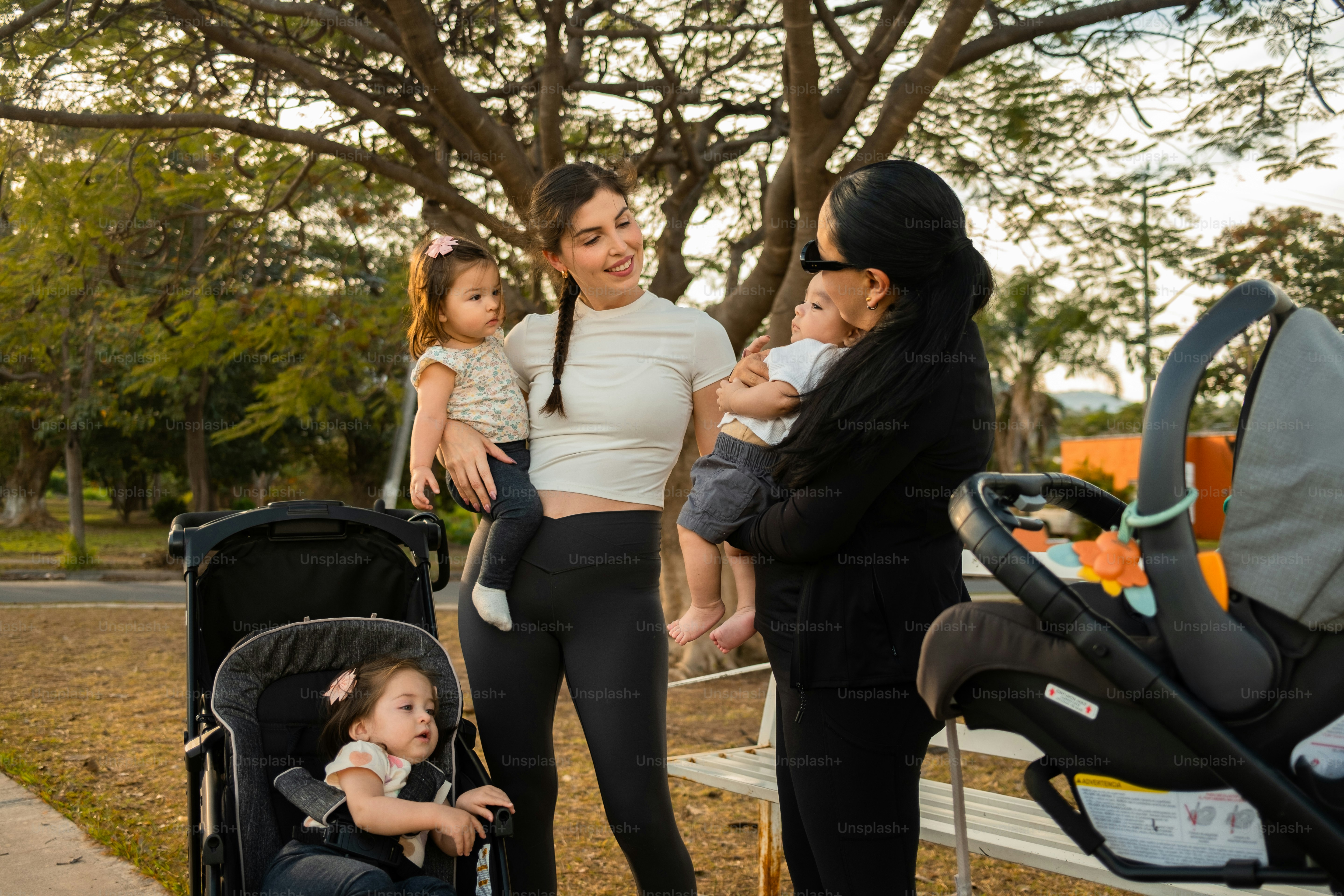Dua wanita dengan bayi dan kereta bayi di taman