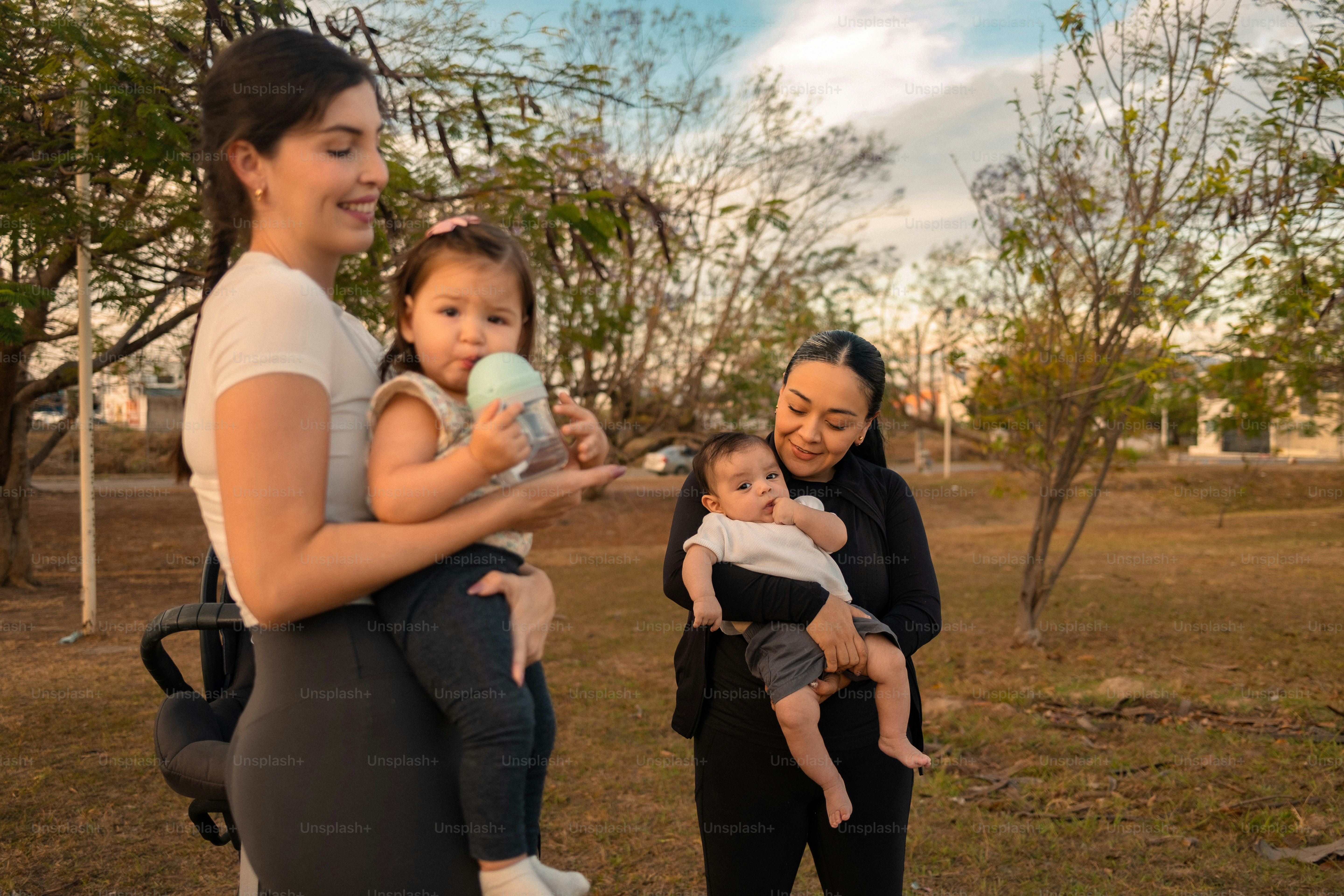 Dua wanita menggendong bayi di taman