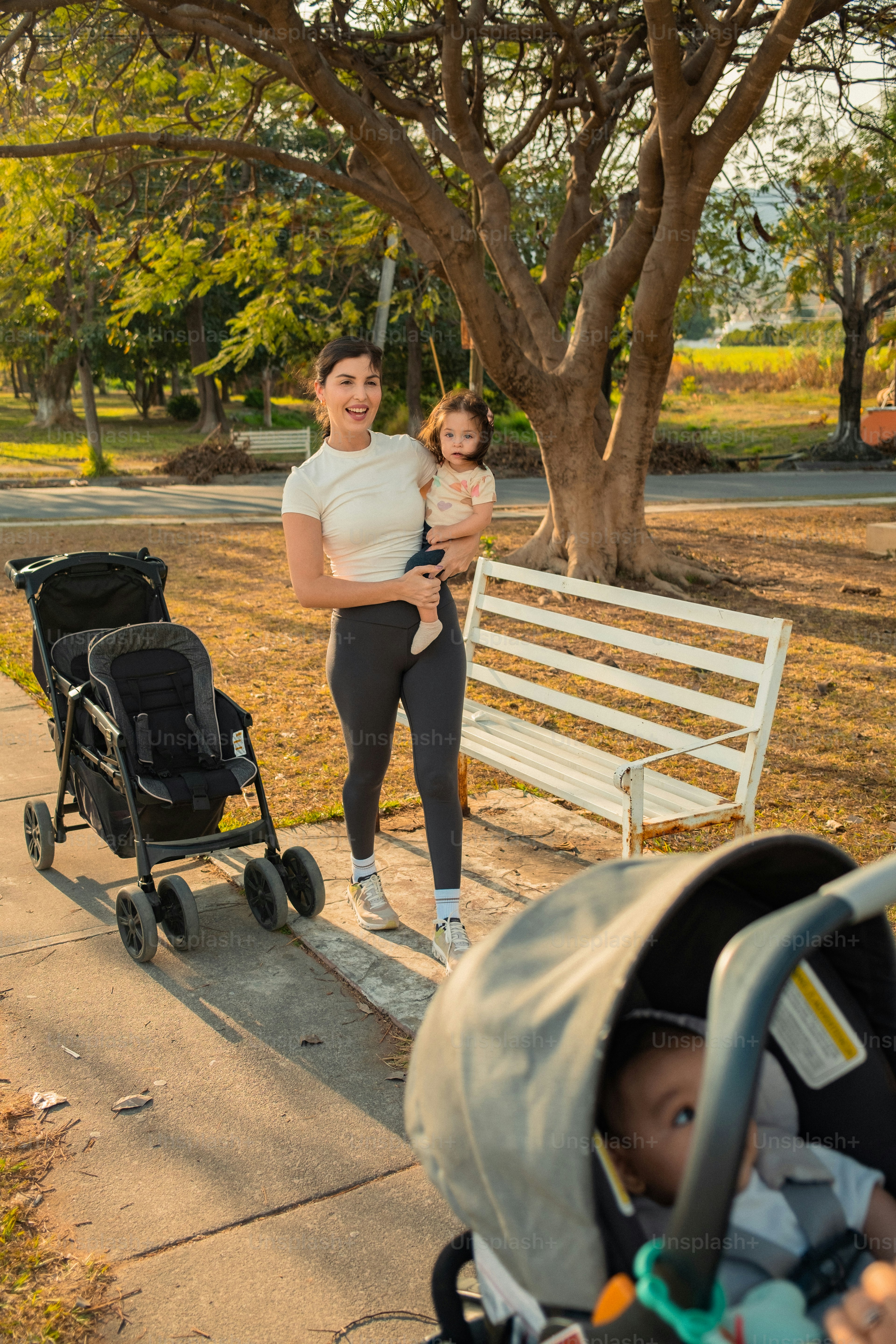 Wanita menggendong bayi dengan kereta dorong di taman