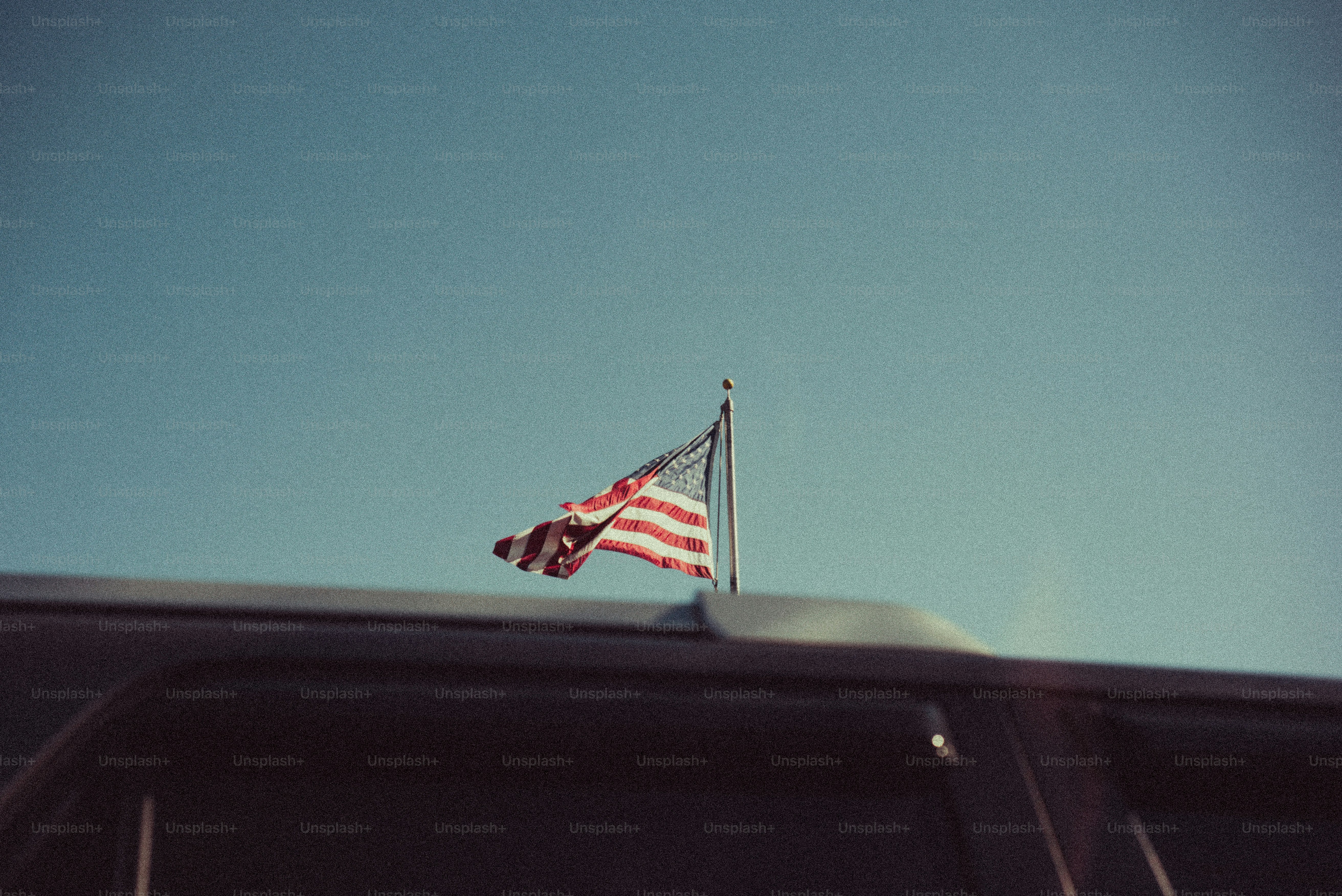 American flag waving on a car roof against blue sky