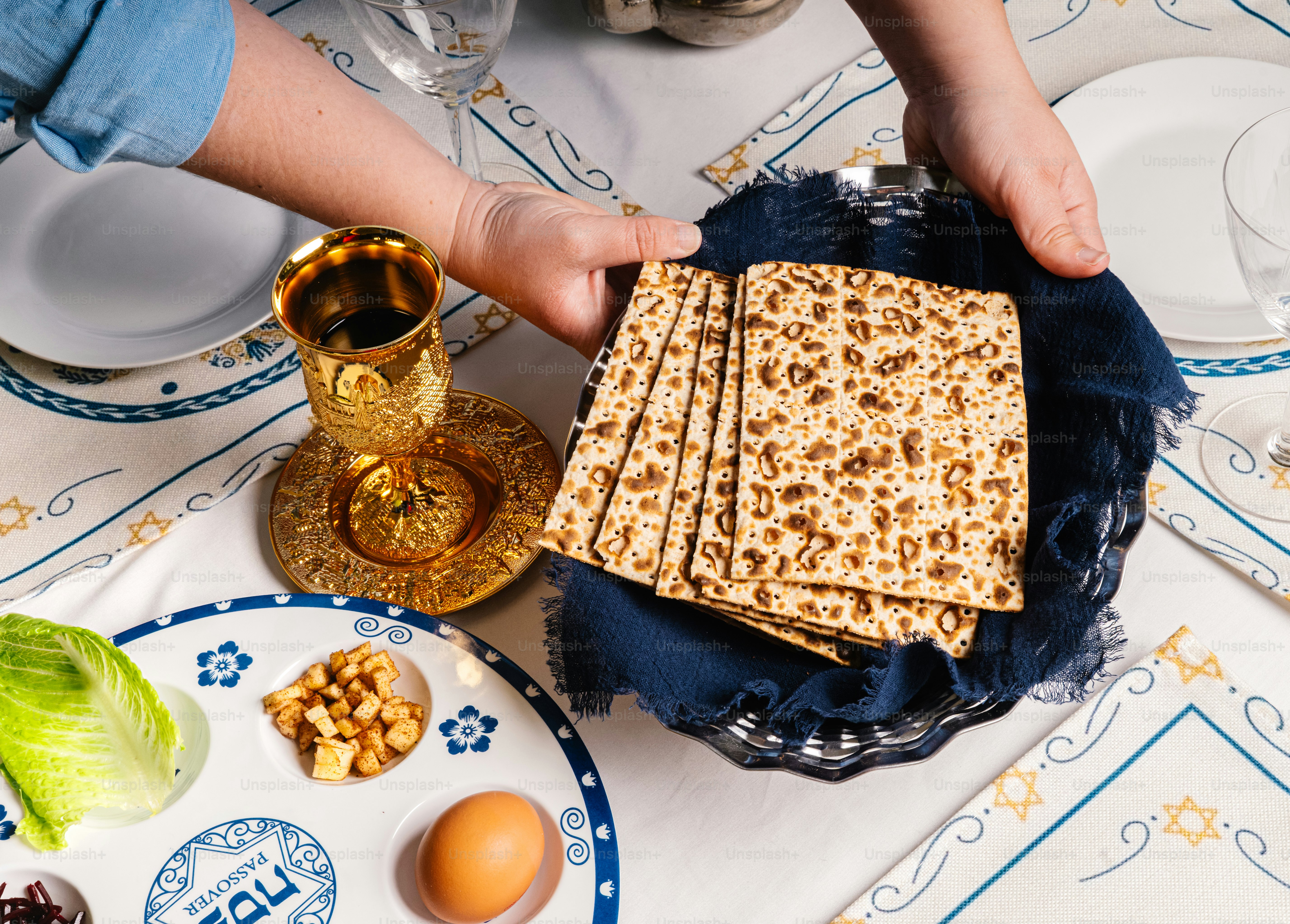 Hands placing matzah on a passover seder plate.
