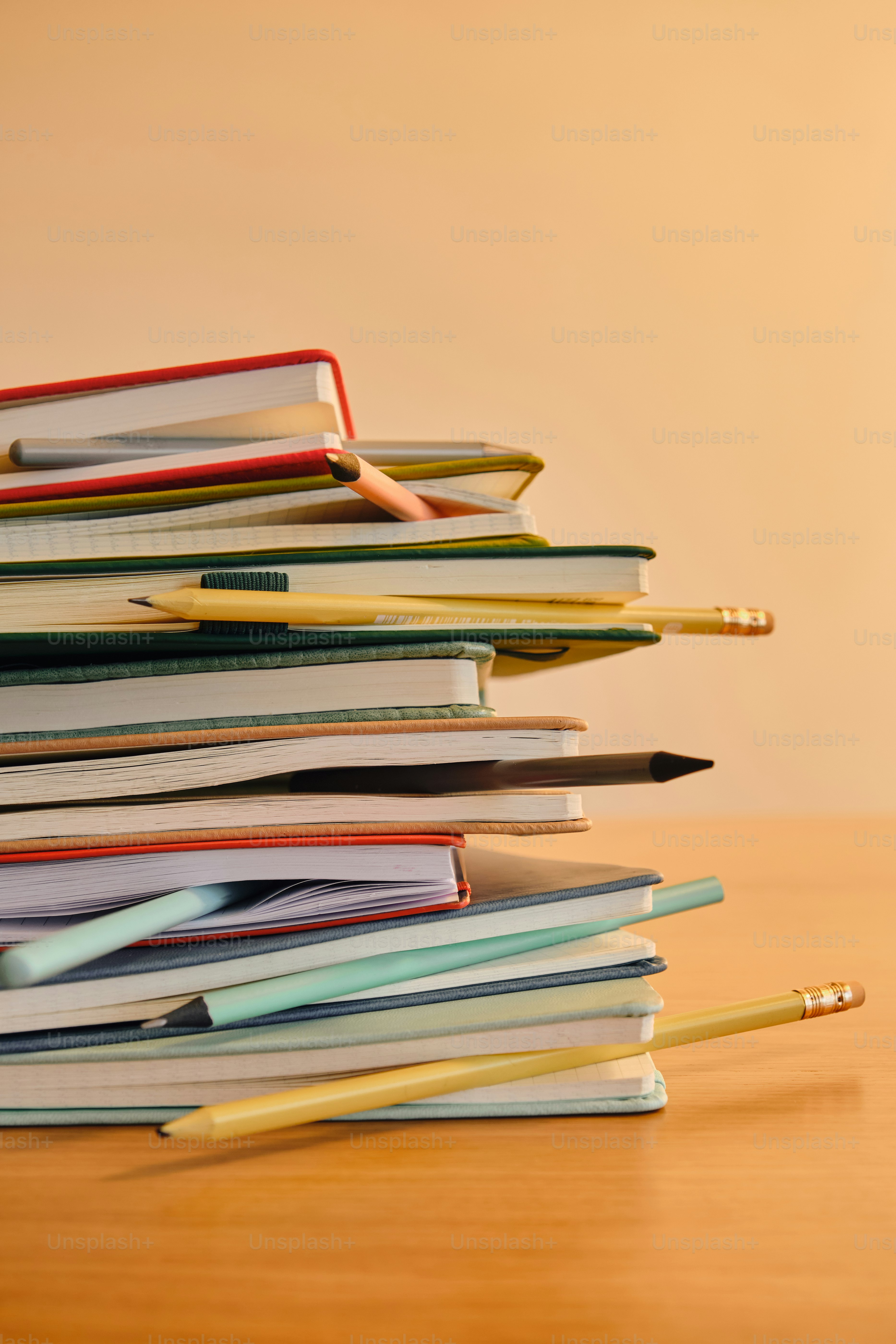 A stack of notebooks with pencils on a wooden table. photo – Office ...