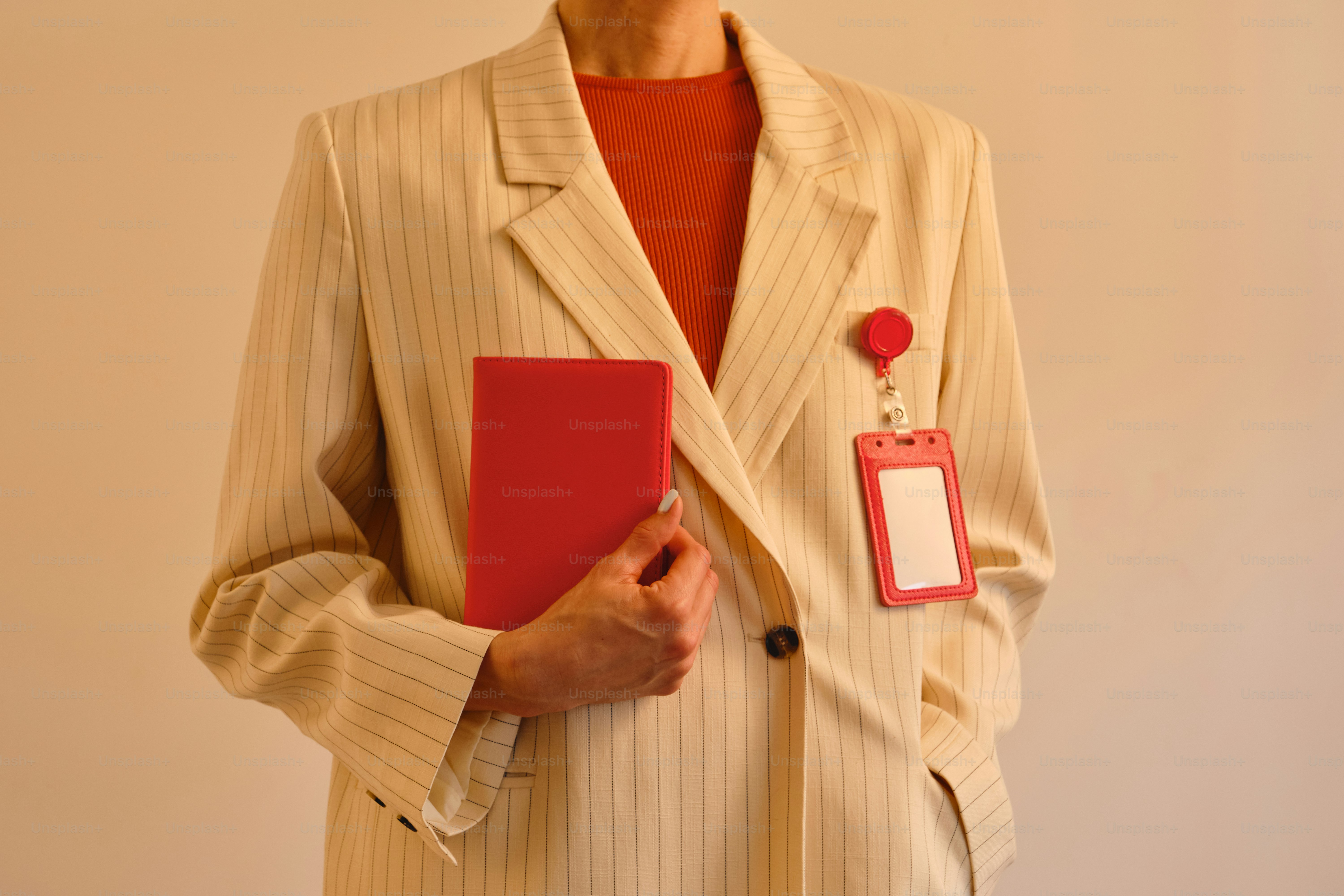 Person in a blazer holding a red book