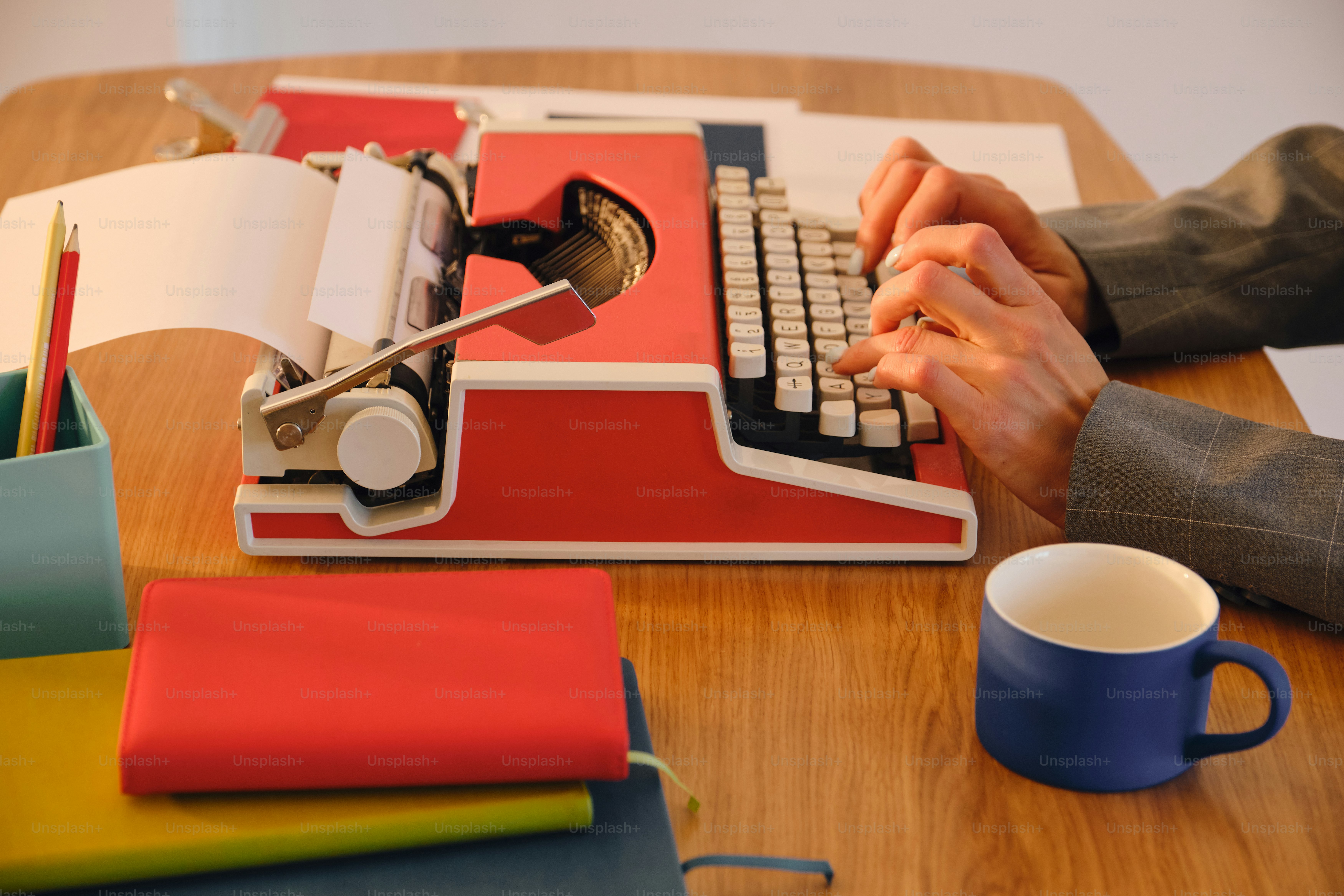 Hands typing on a vintage typewriter at a wooden desk.