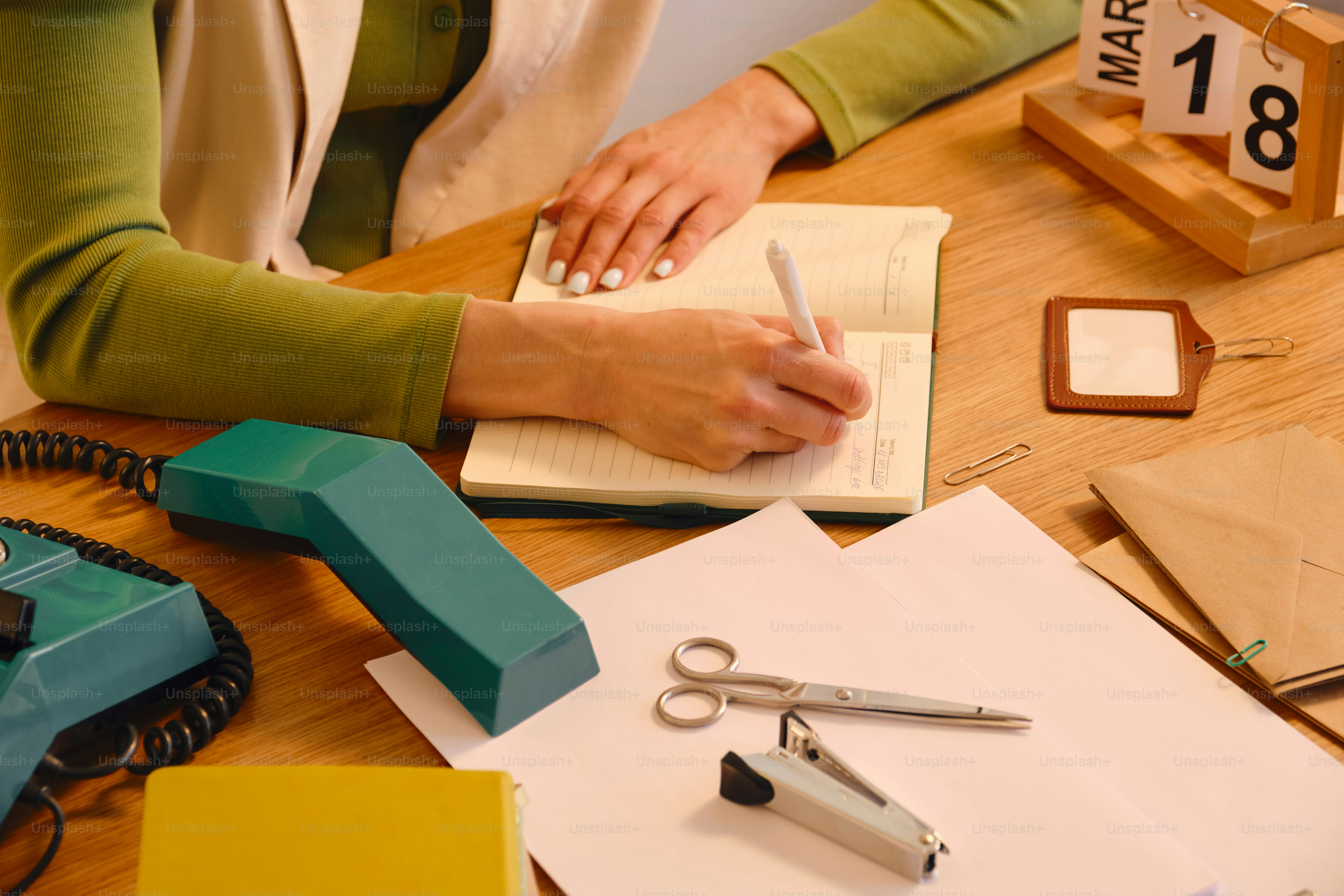 A person writing in a notebook at a desk.