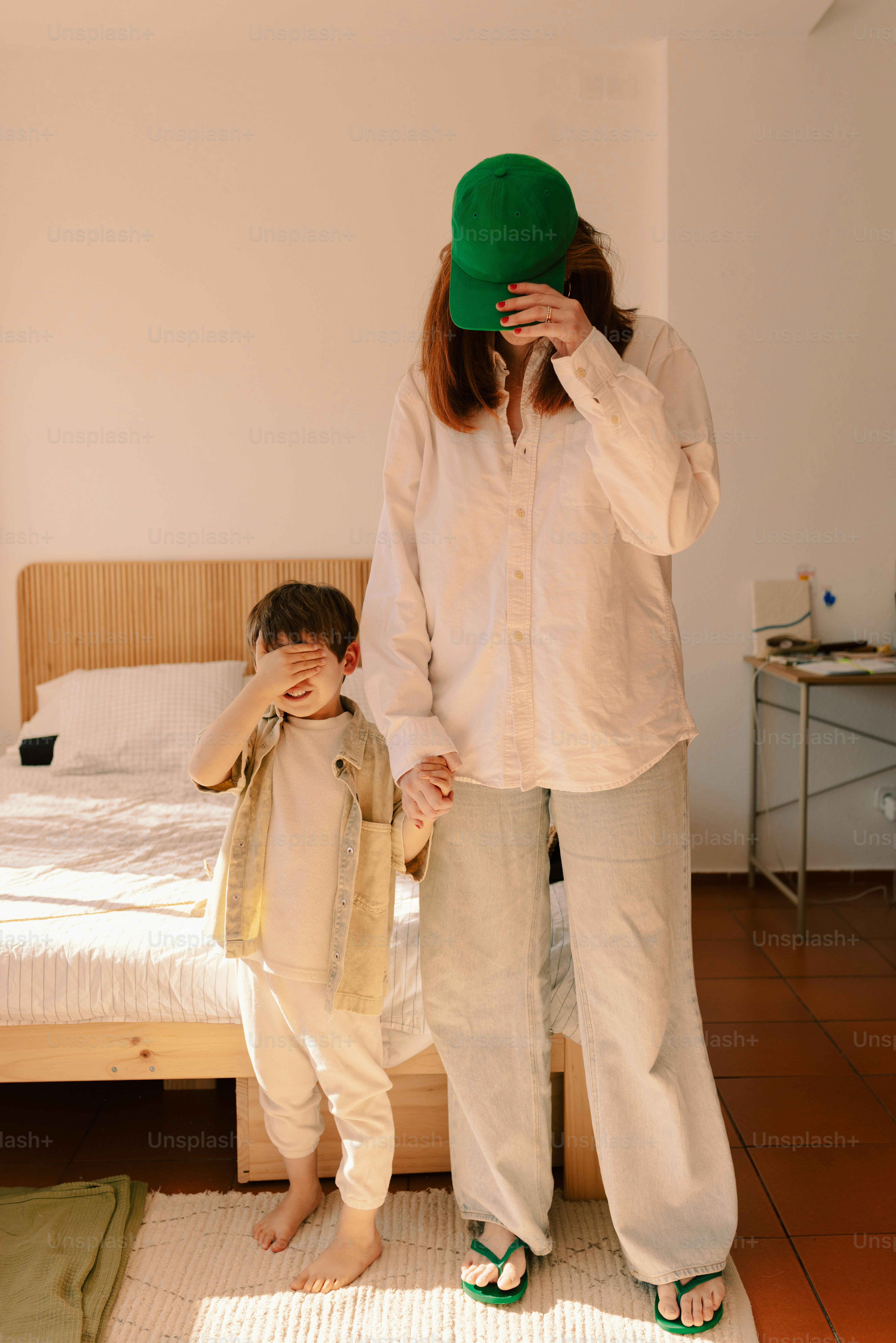 Adult and child covering eyes in a bedroom