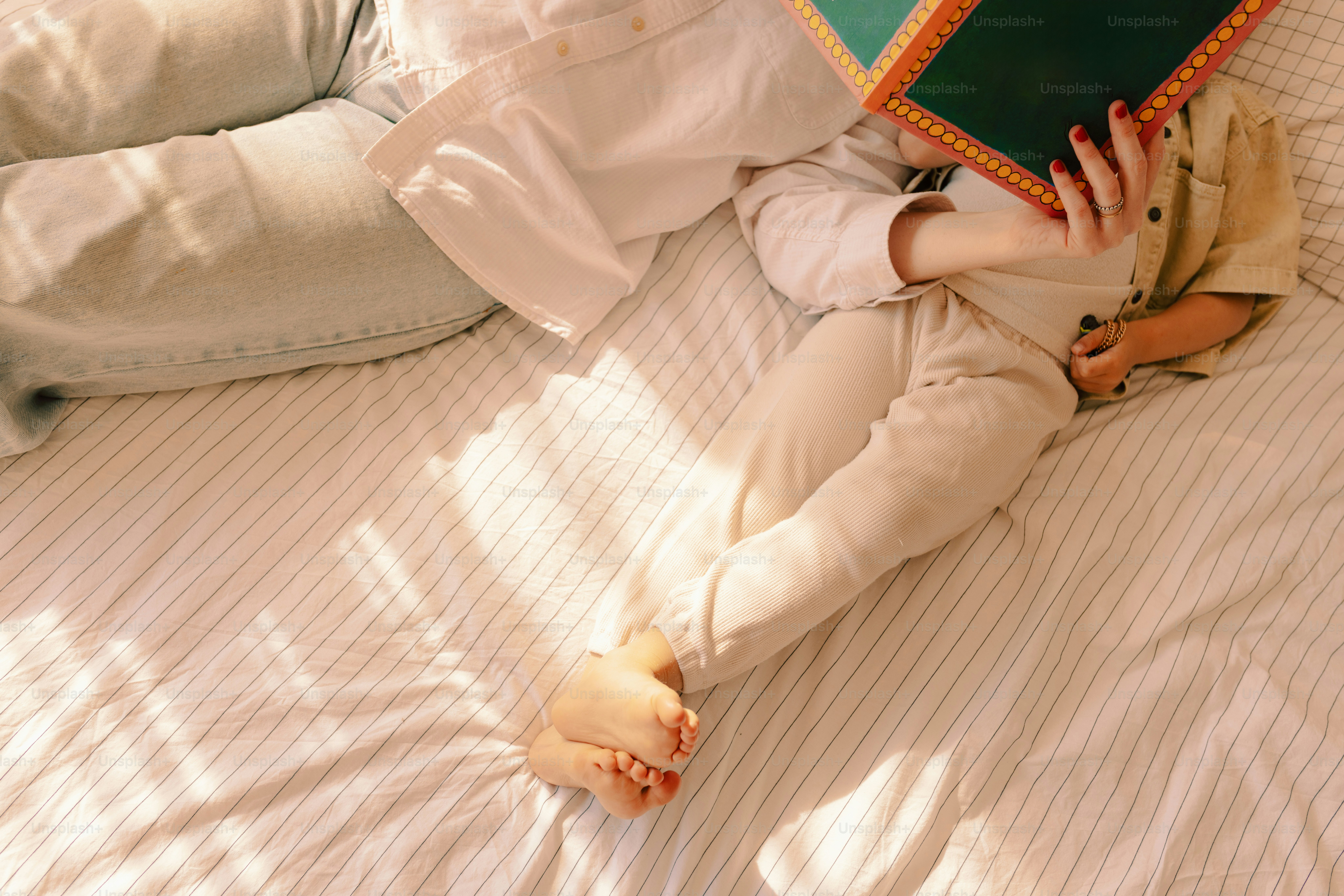A person and child reading a book in bed.
