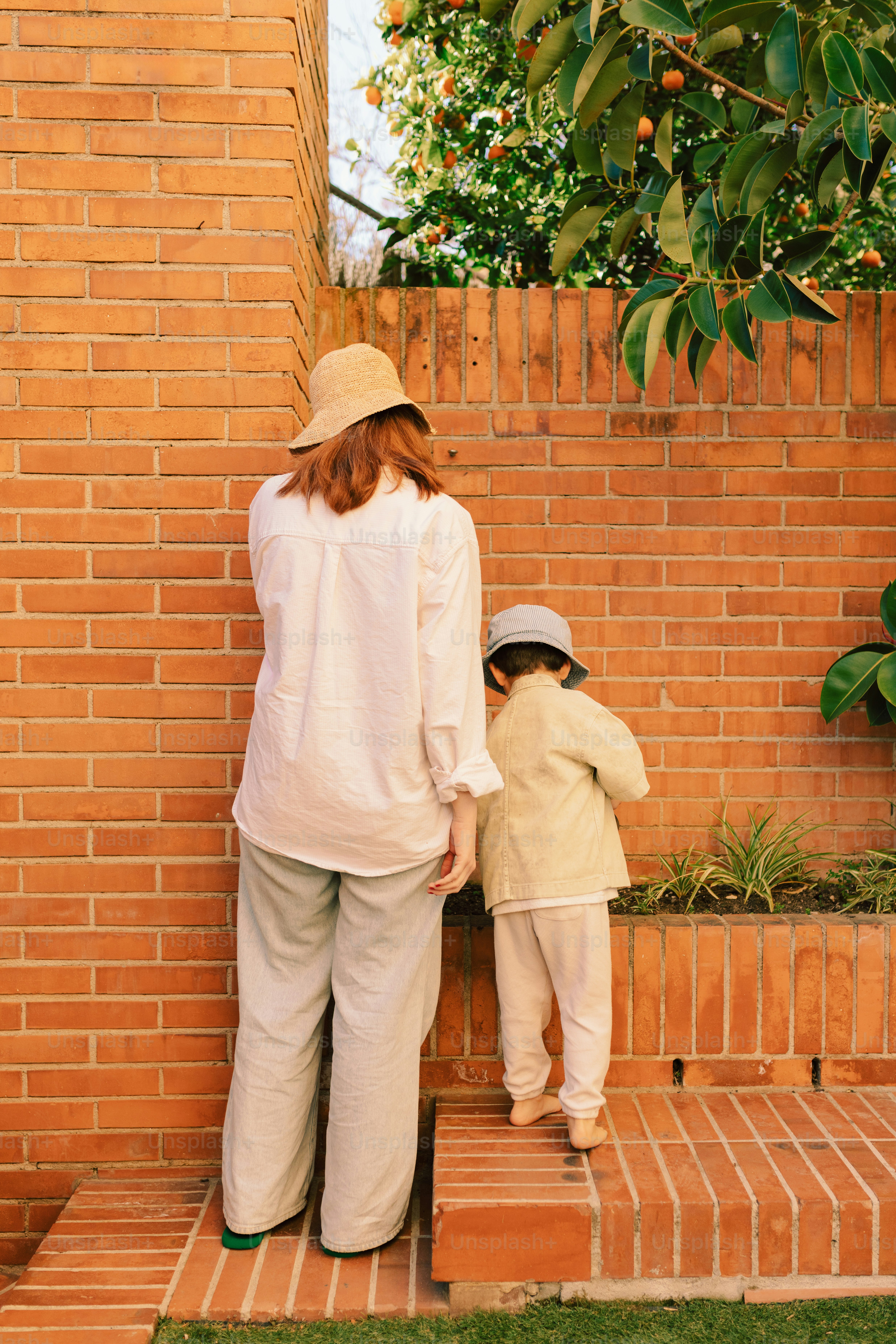 Woman and child by brick wall near plants