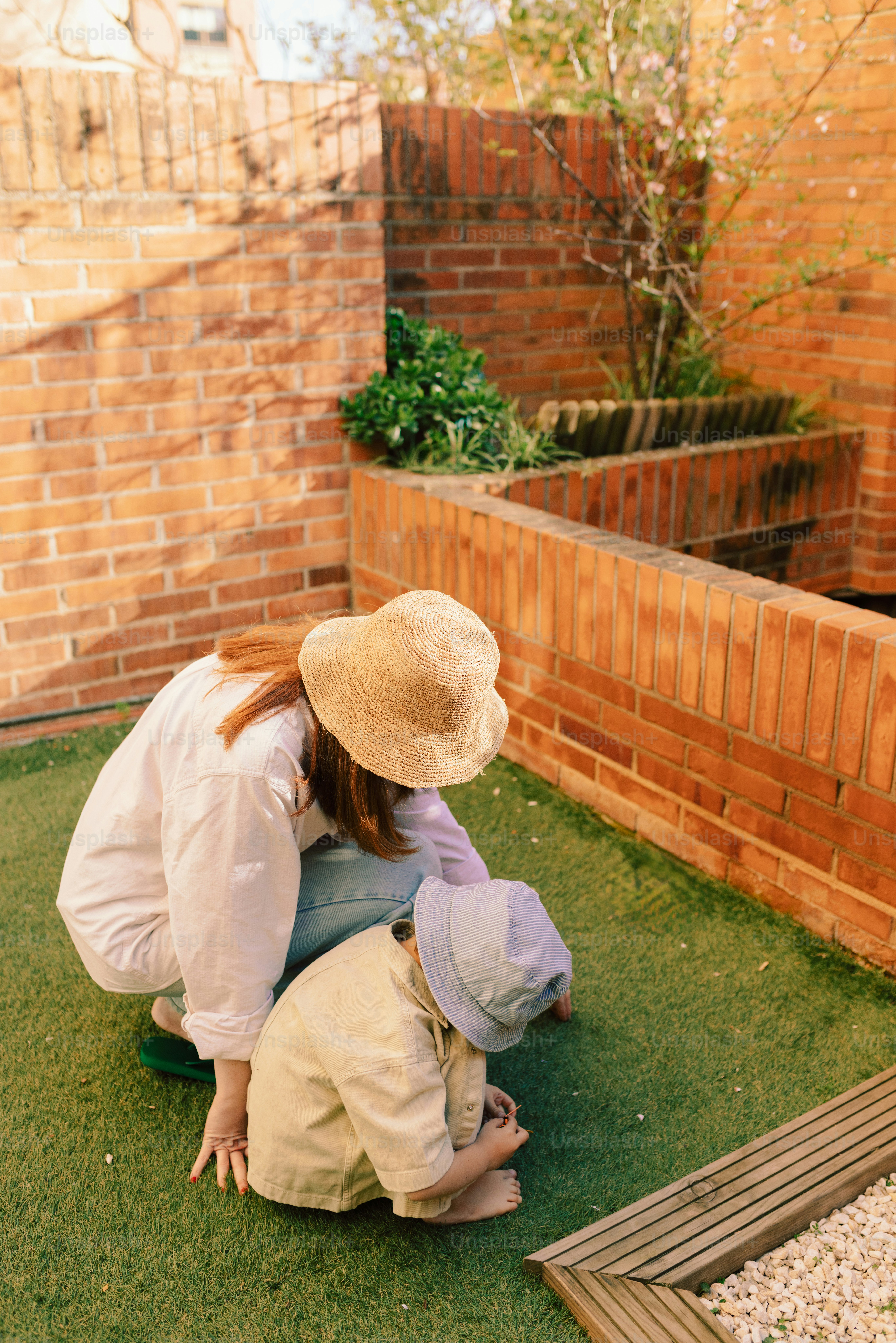 Woman and child looking at something on the grass.