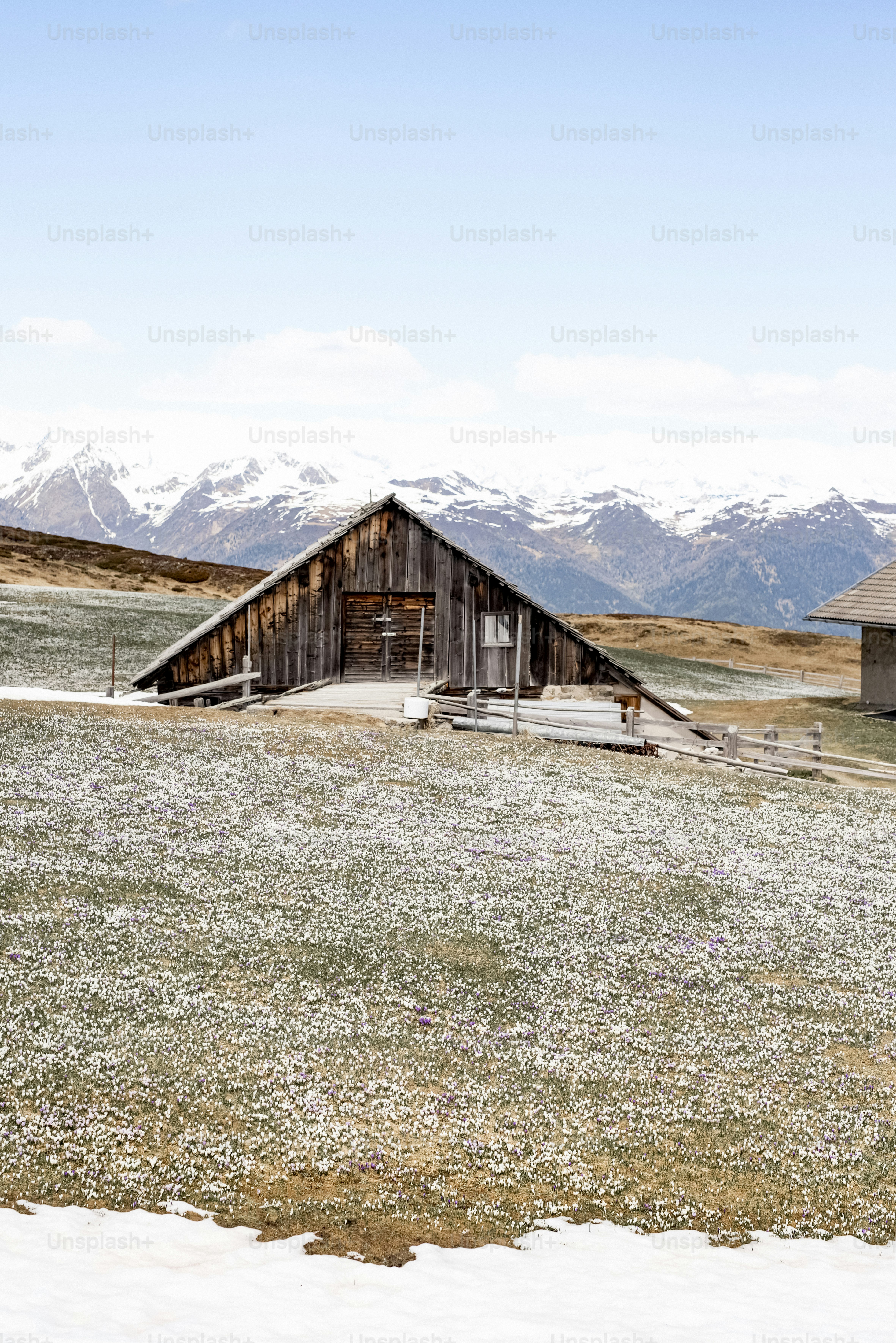 눈 덮인 산악 풍경 속의 나무 헛간