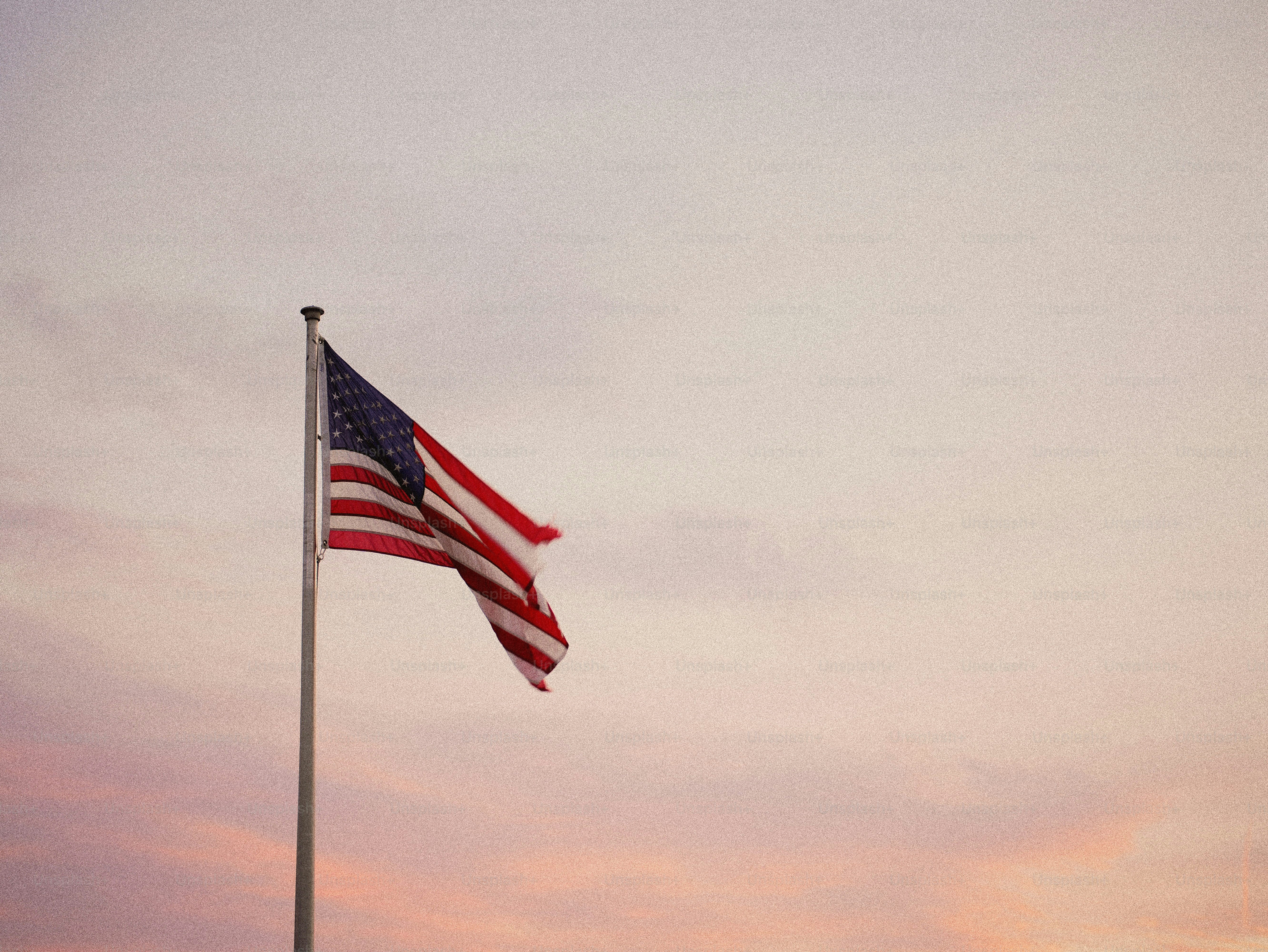 American flag waving against a pastel sky