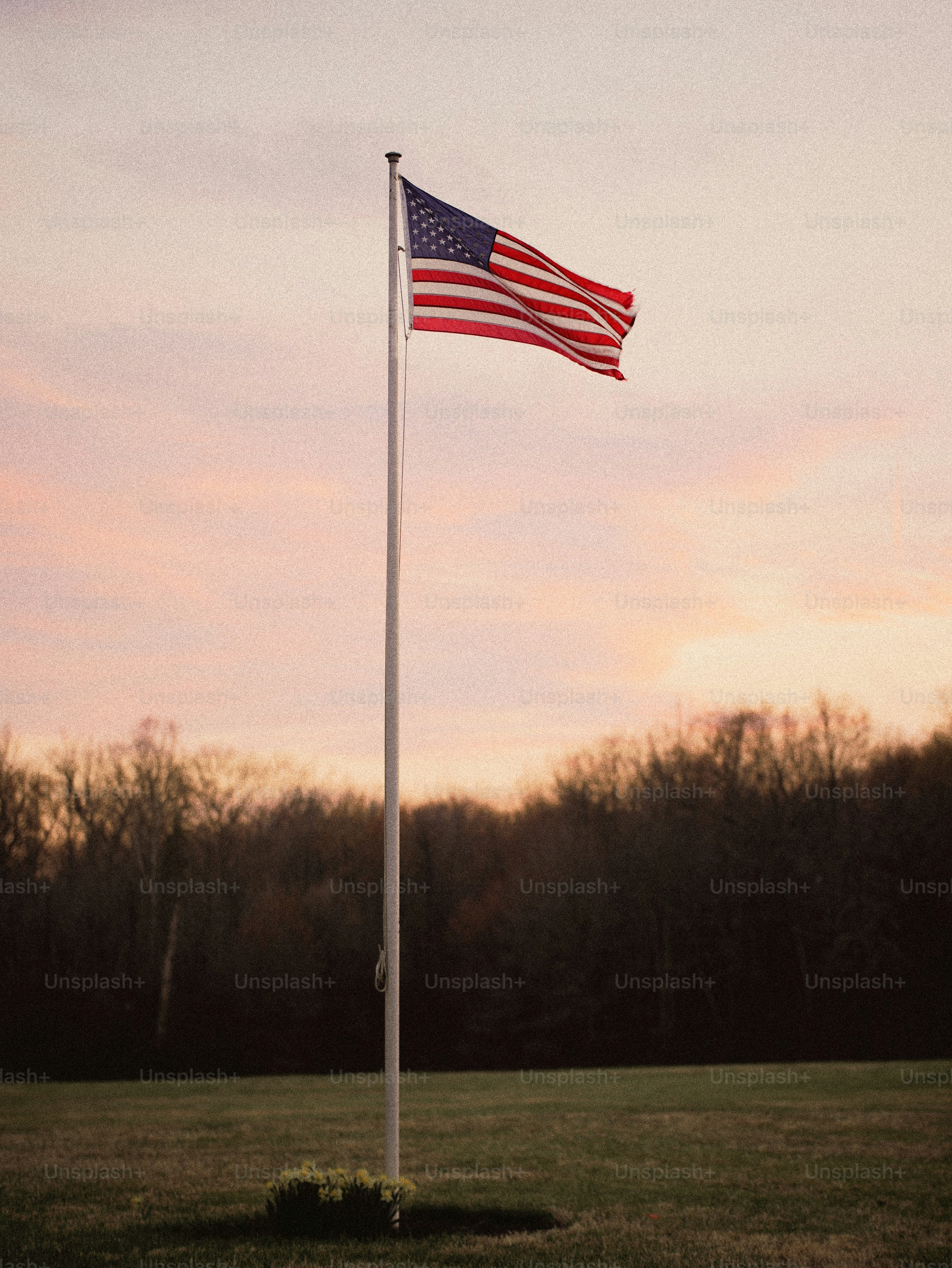 American flag waves on a tall pole at sunset