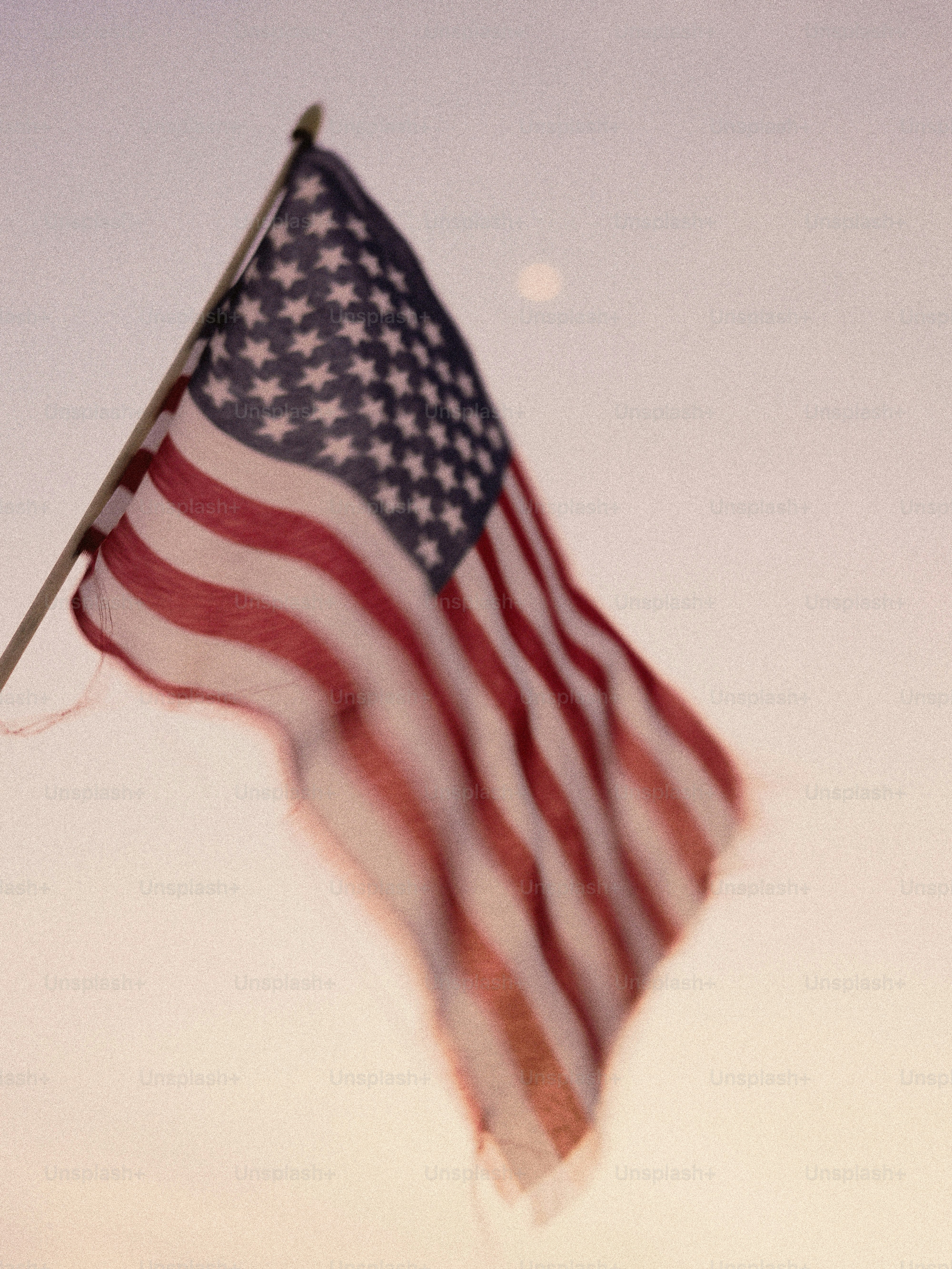 American flag waving against a pale sky.