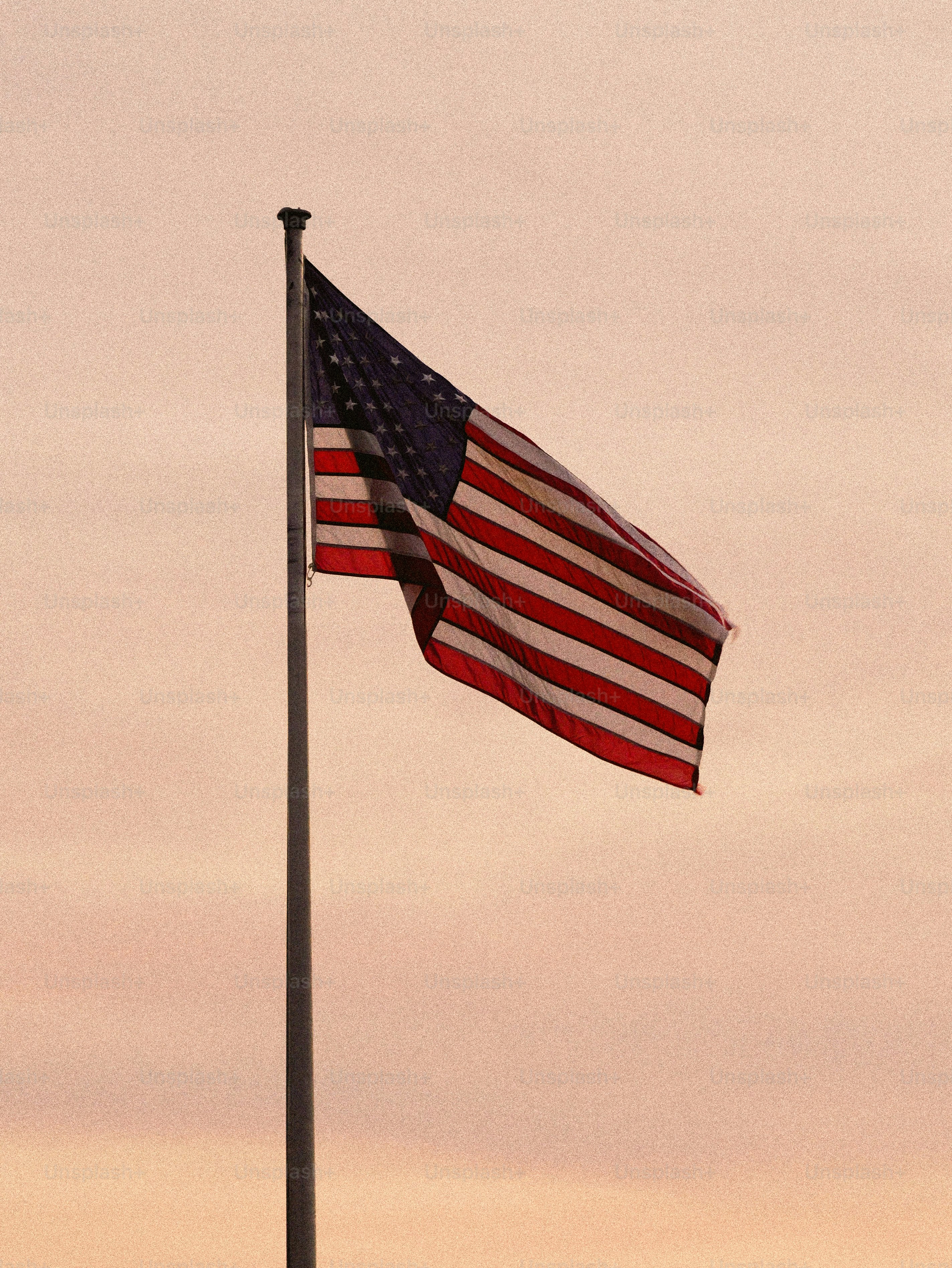 American flag waving on a flagpole at sunset