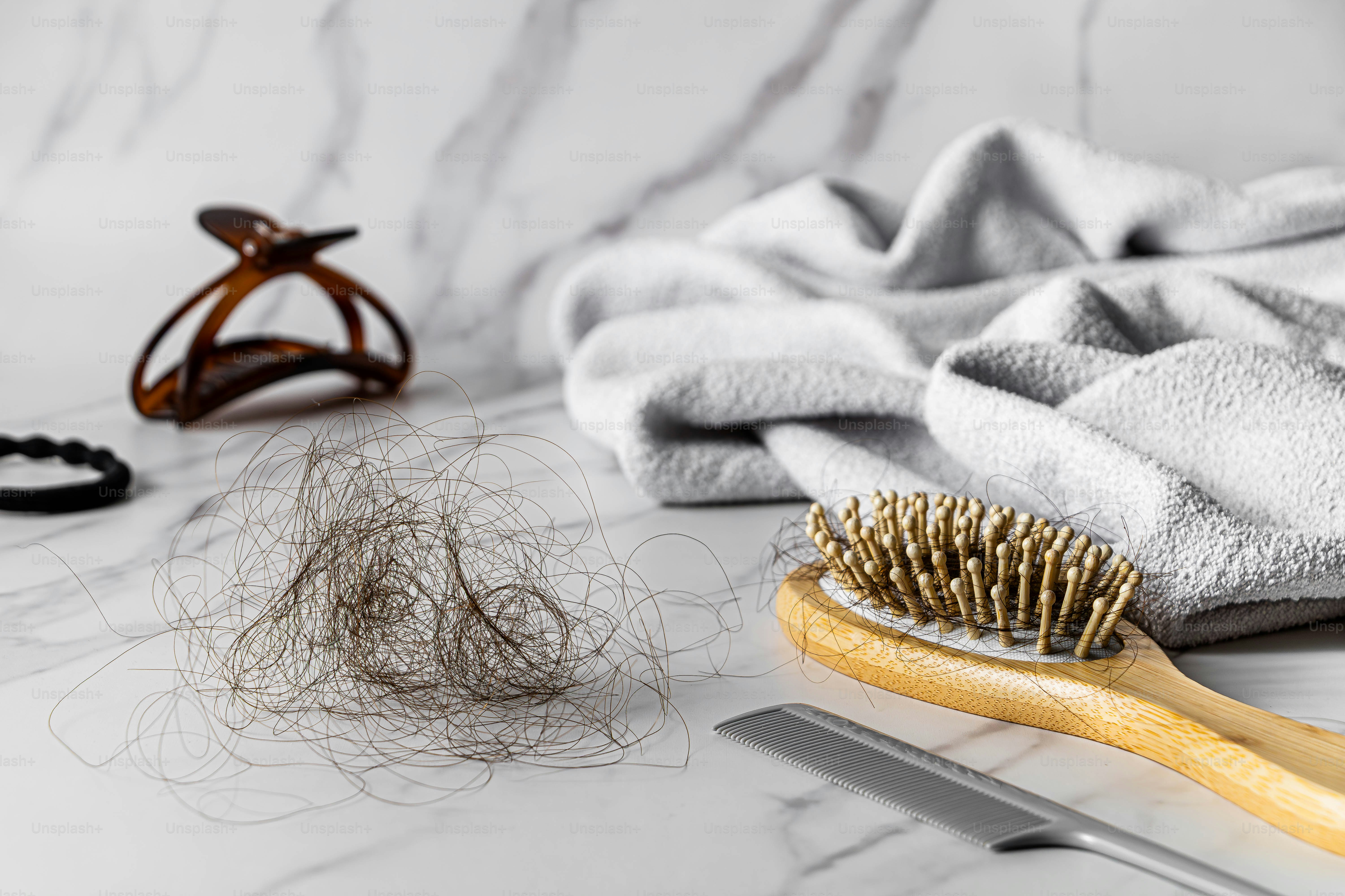 Haarbürste mit gefallenem Haar und Haaraccessoires auf Marmor