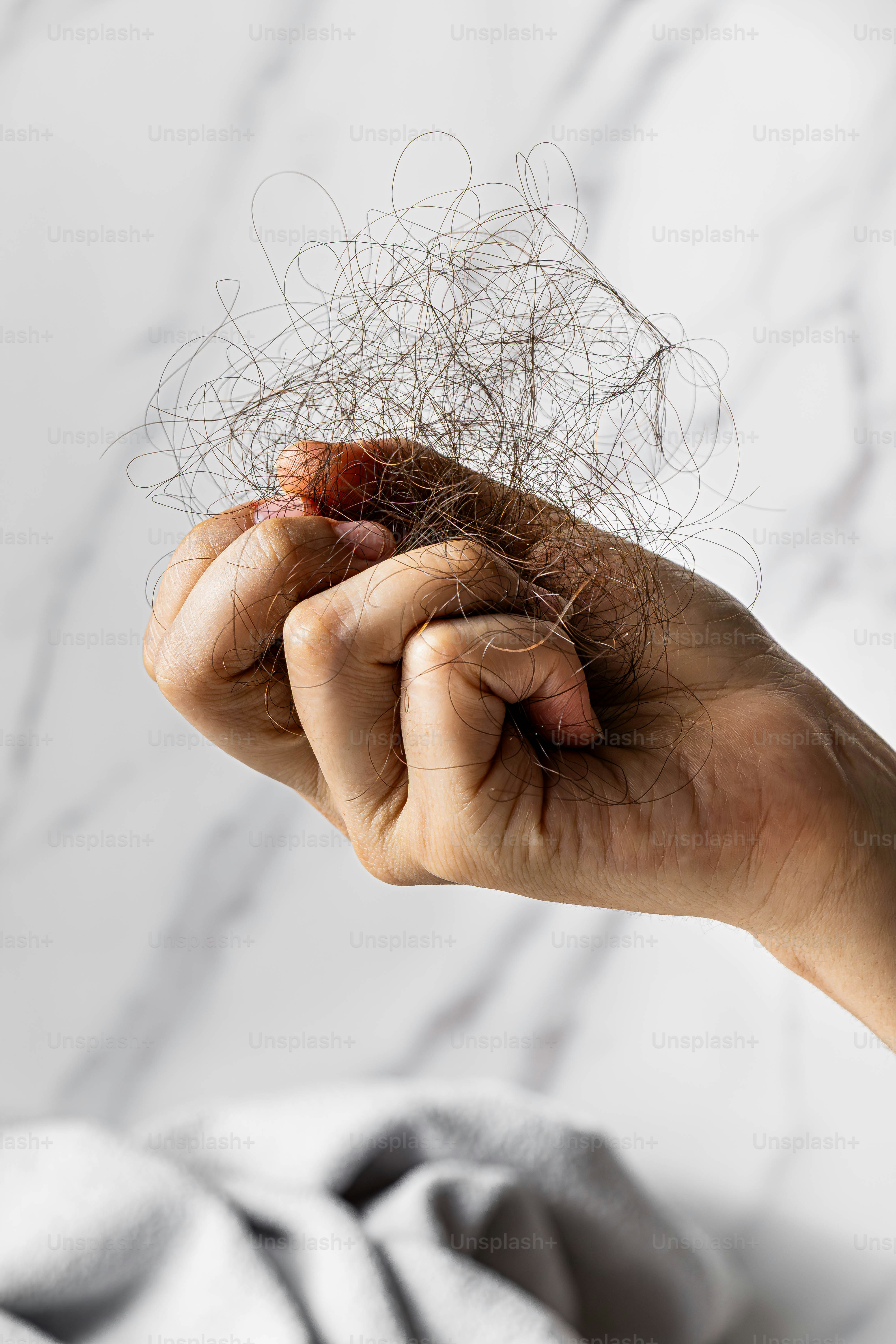 Hand hält einen Büschel heruntergefallener Haare