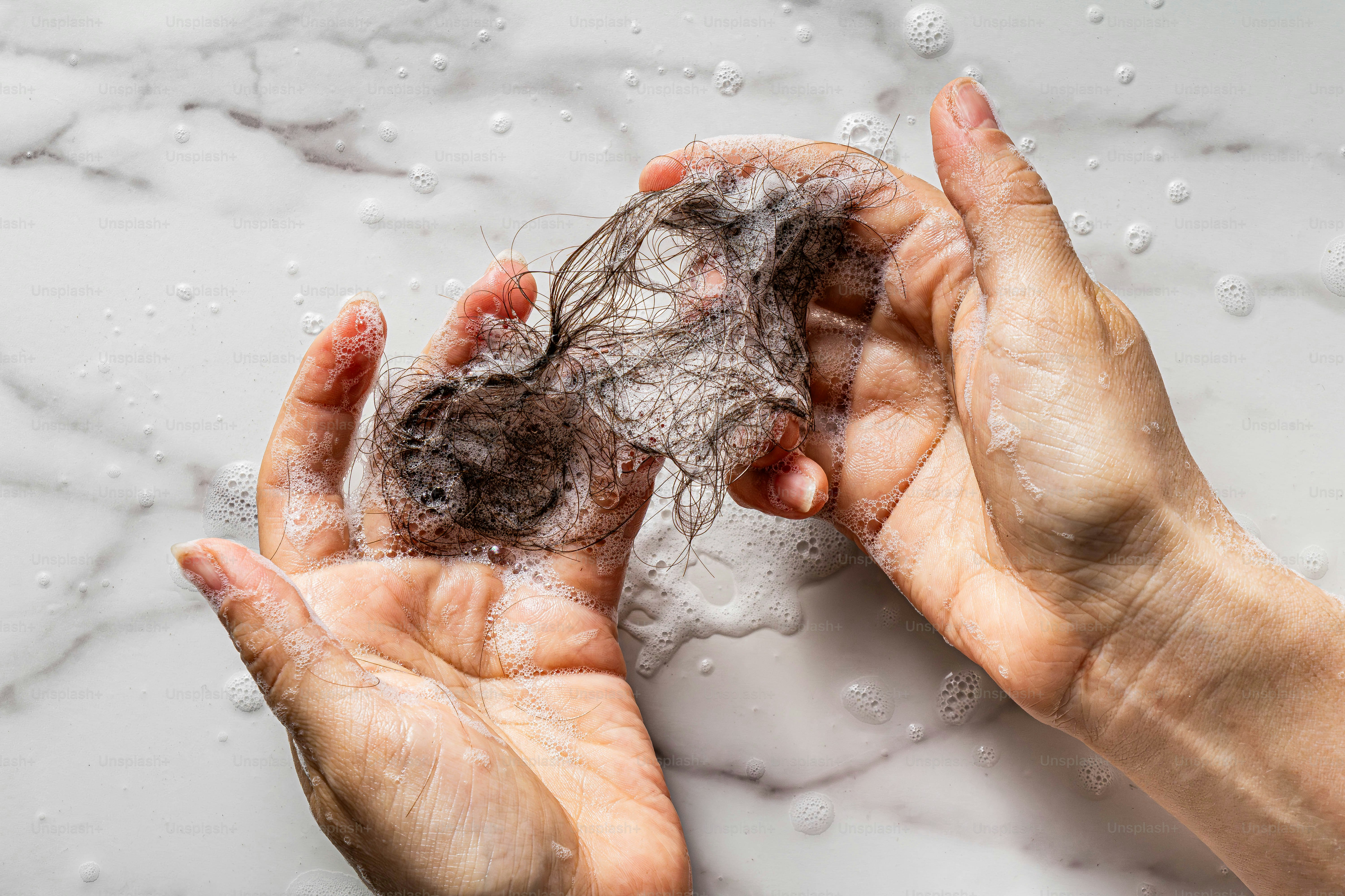 A hand holds a clump of fallen hair. photo – Hand Image on Unsplash