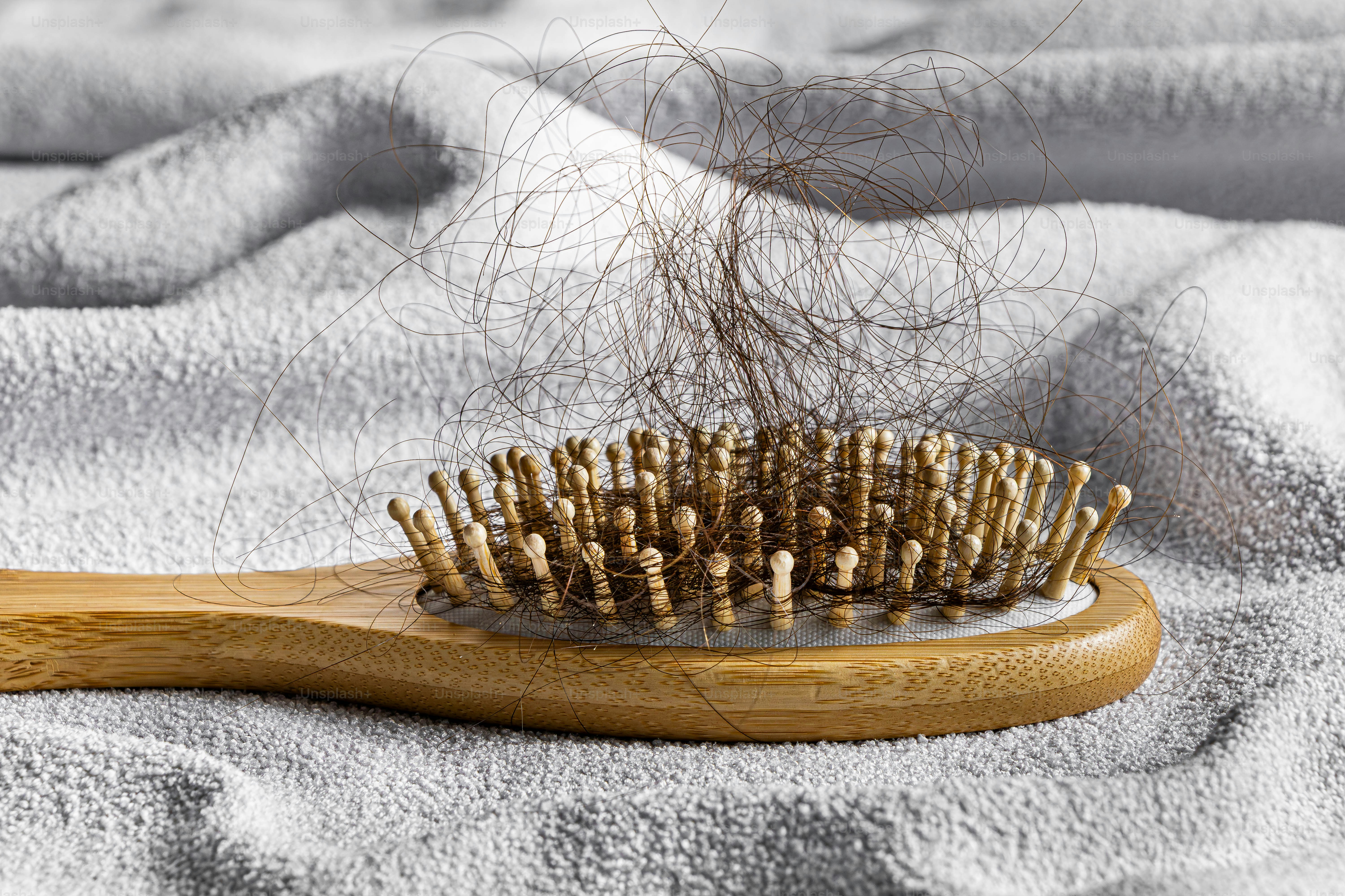 Haarbürste auf einem Handtuch mit abgefallenem Haar.