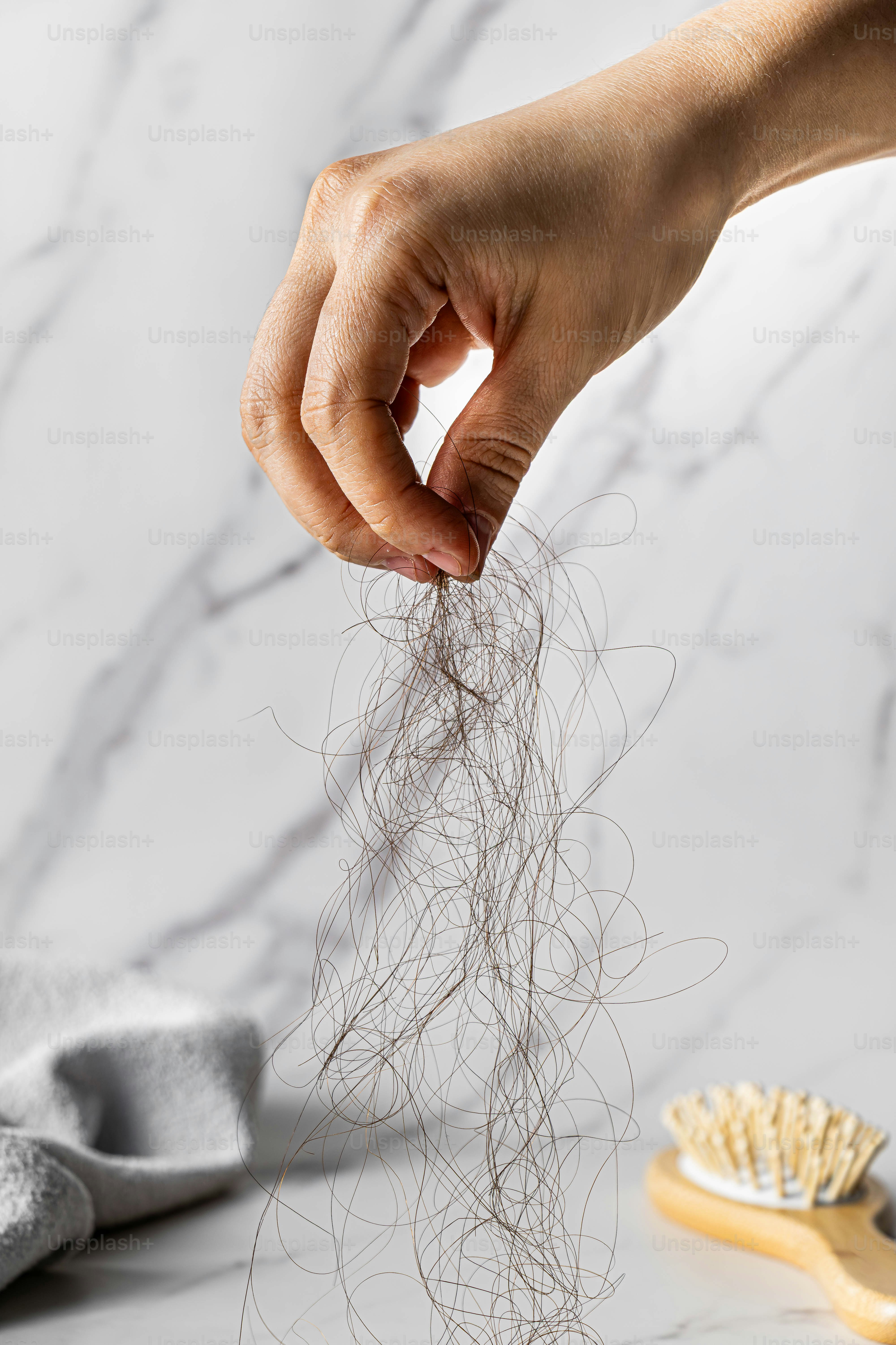 Hand hält sie abgefallene Haarsträhnen mit der Bürste