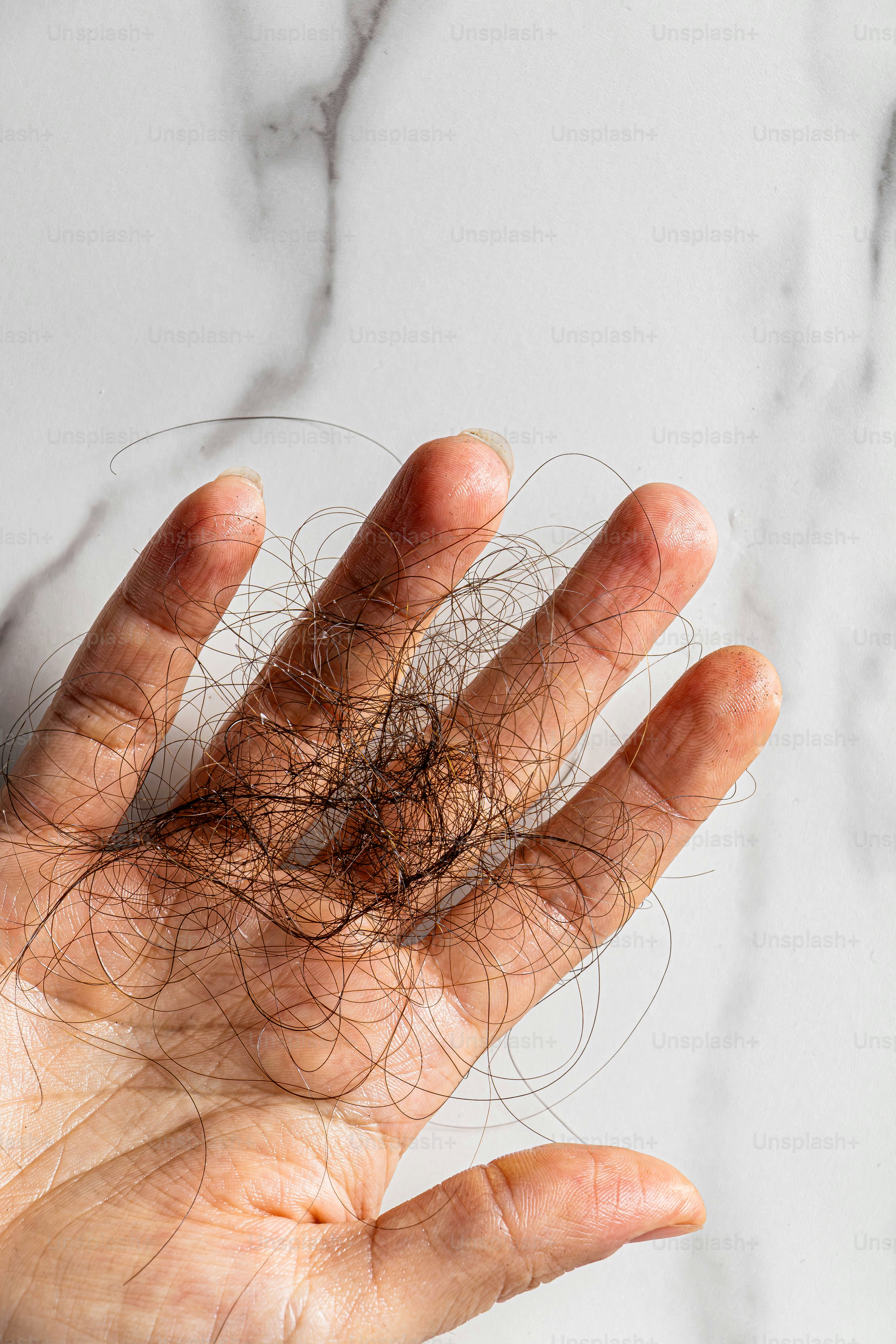 Hand hält einen Büschel heruntergefallener Haare