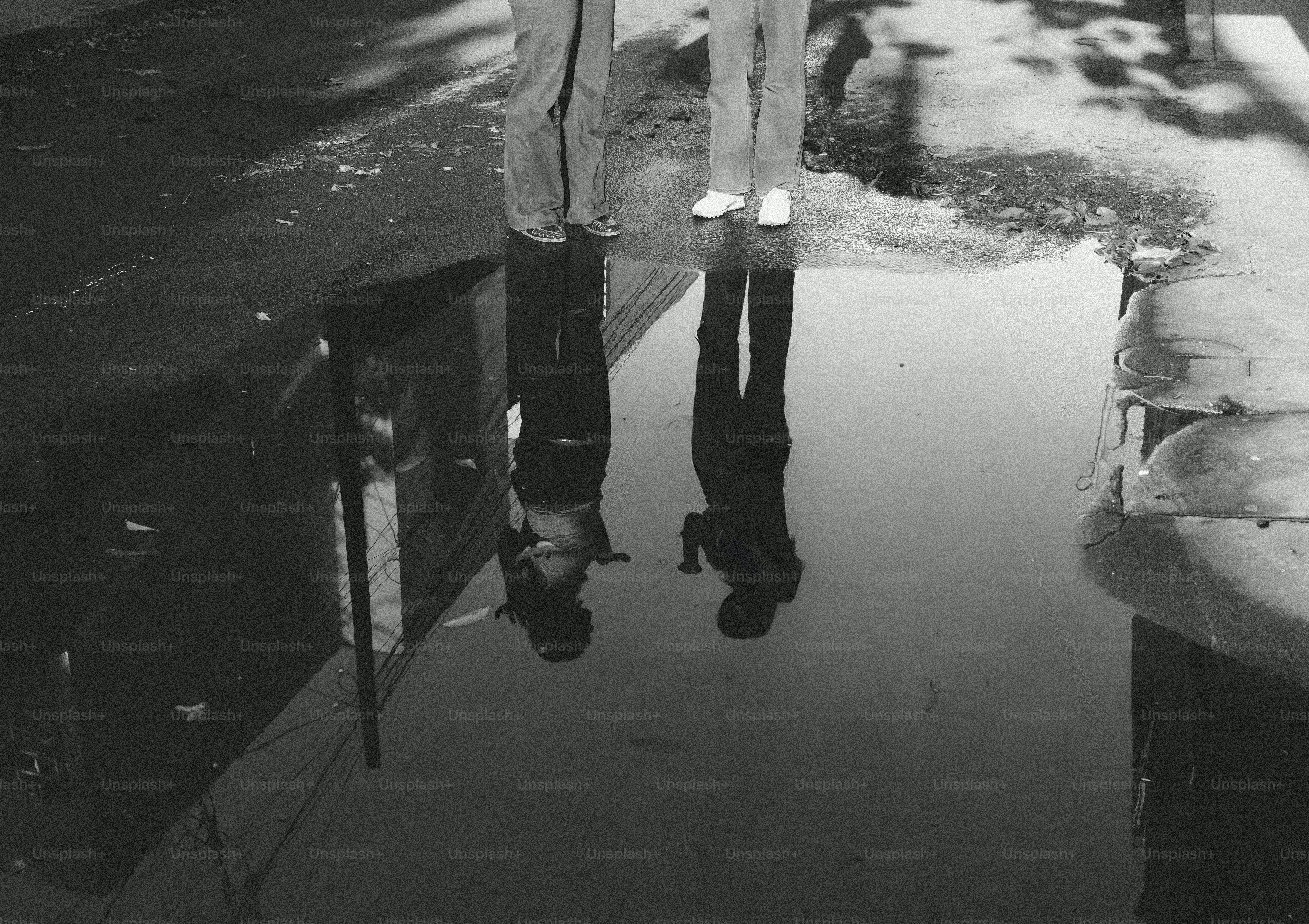 Two people's reflections in a puddle.