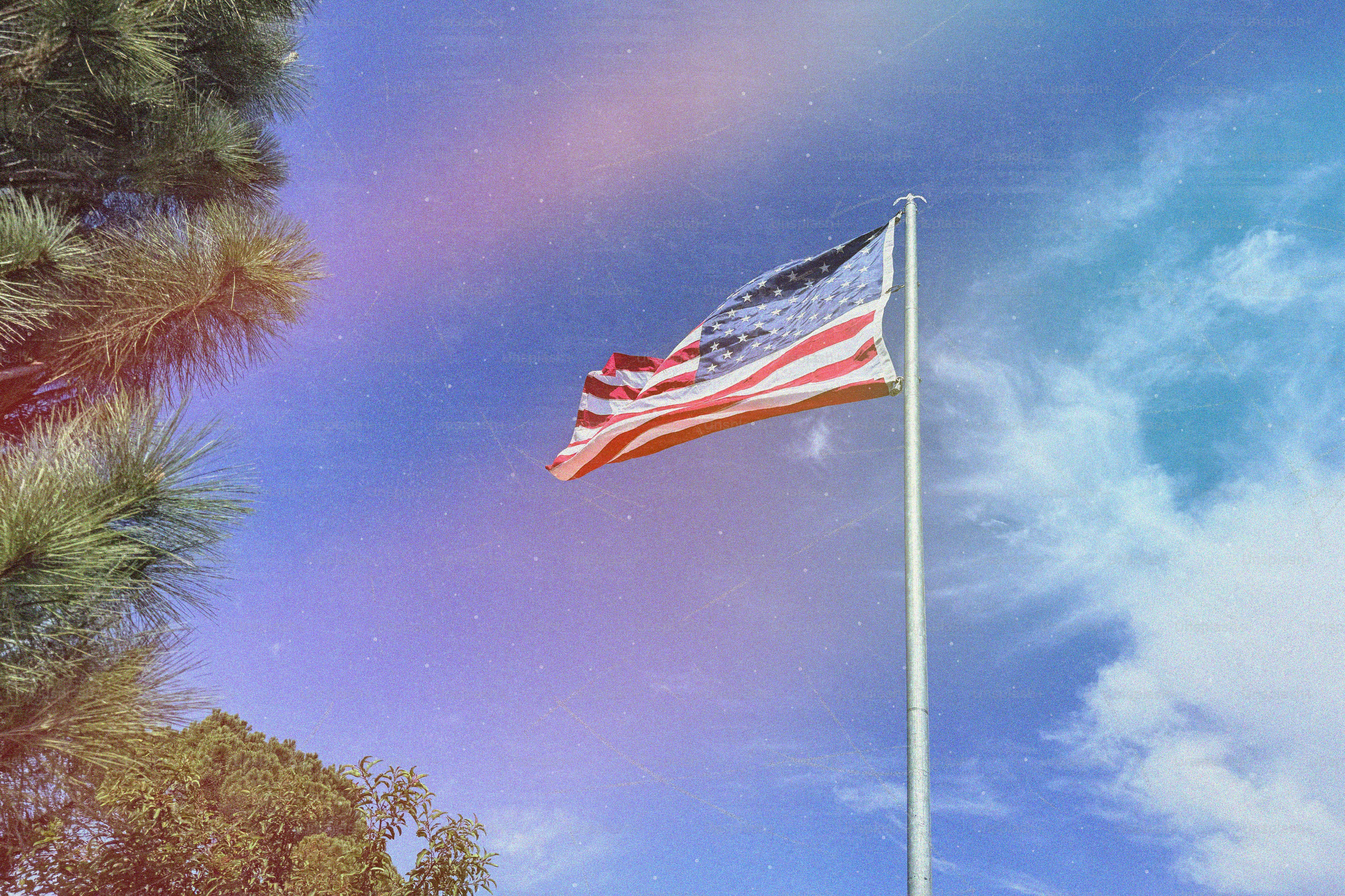 American flag waving against a cloudy blue sky
