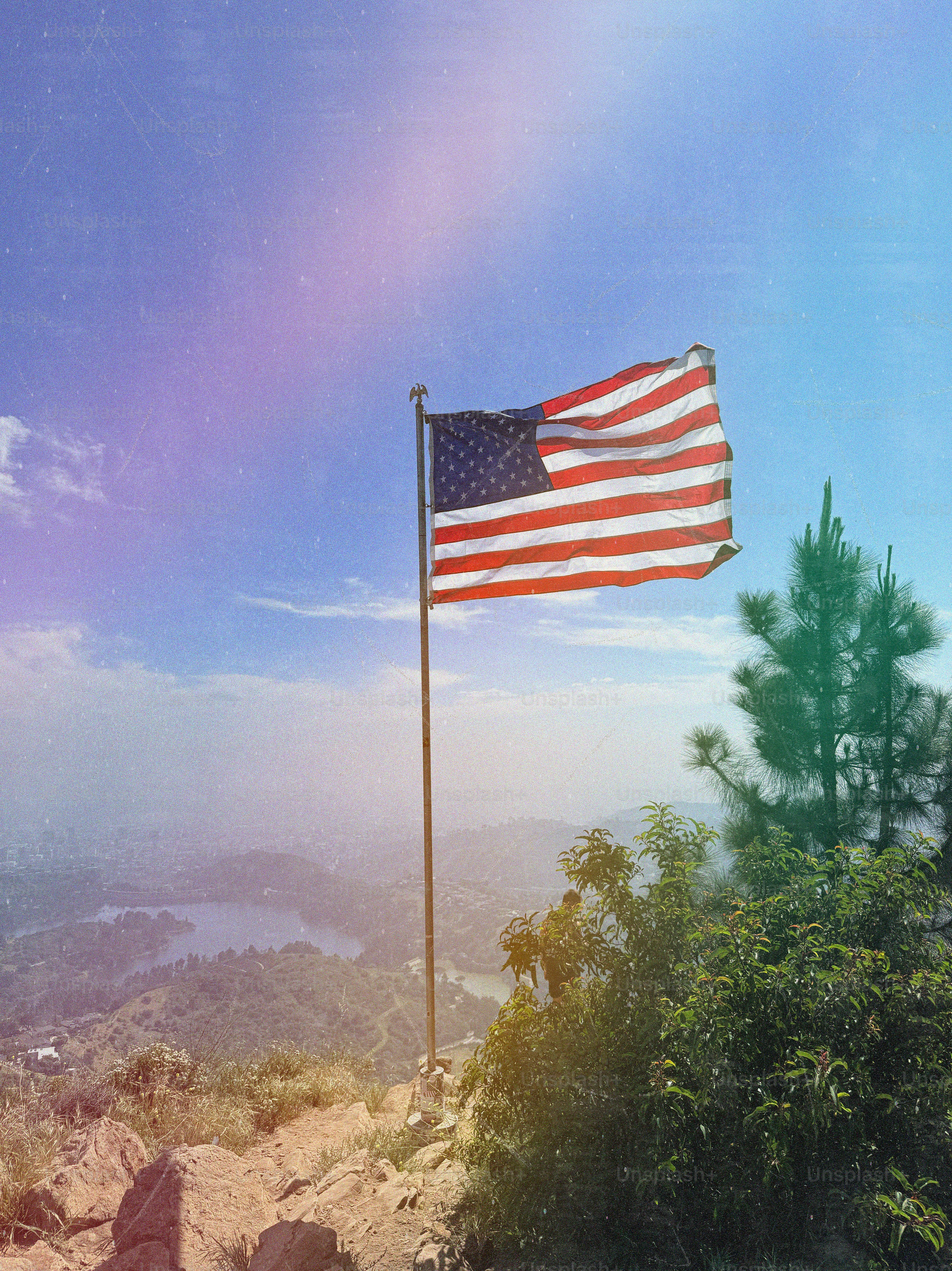 American flag waving on a hilltop overlooking a valley.