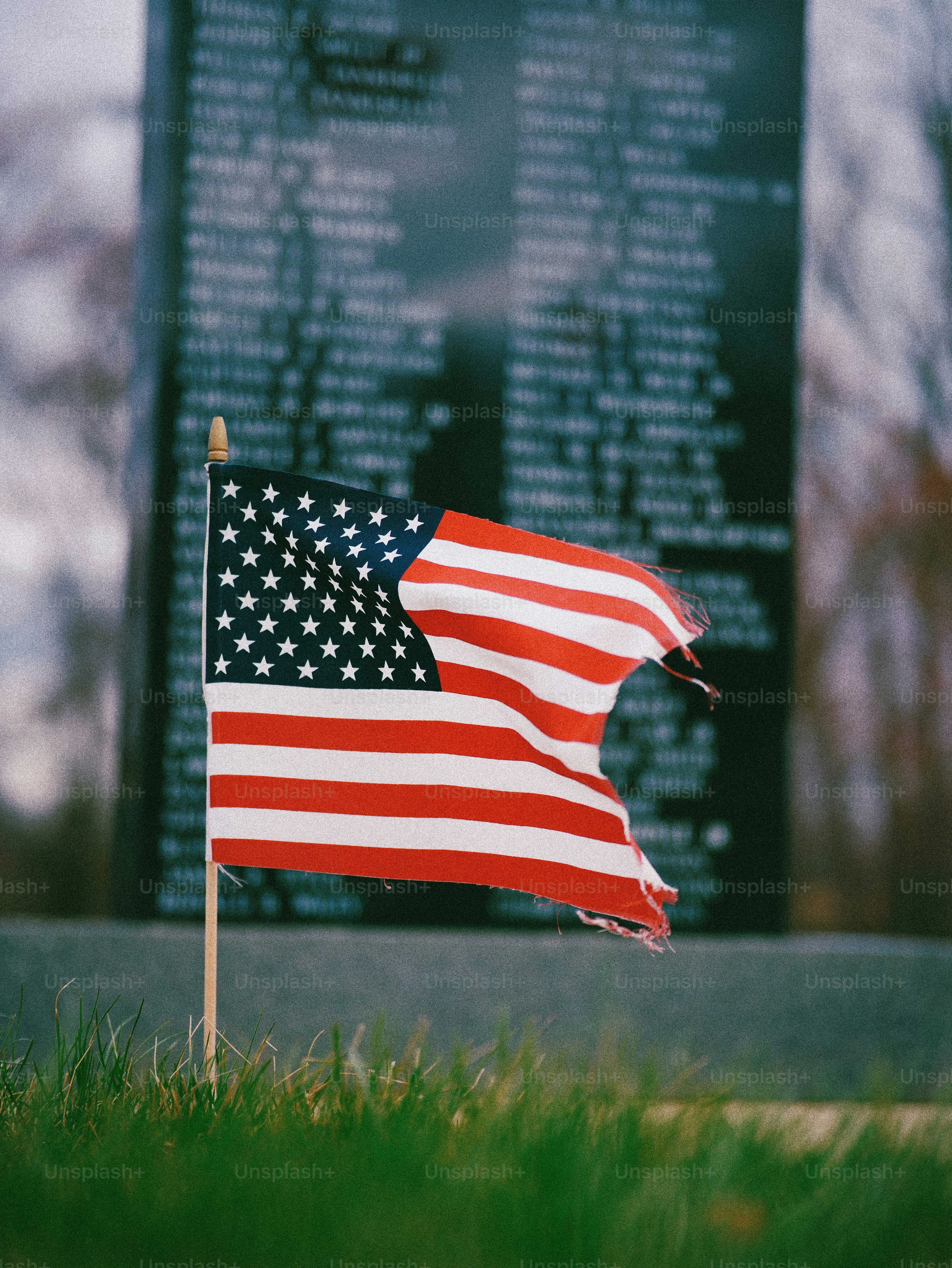 American flag flies in front of a memorial wall