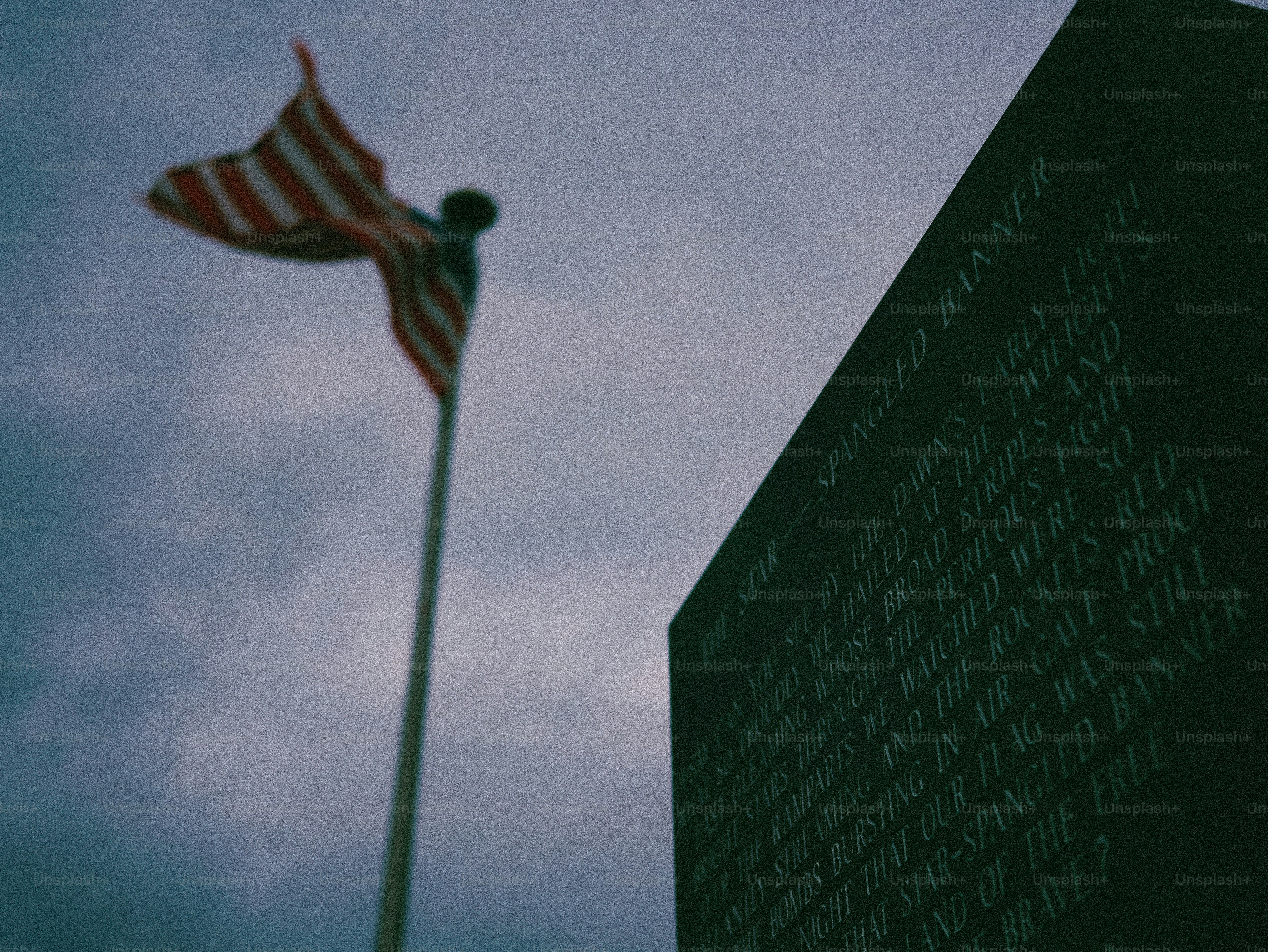 American flag waves near a monument with inscribed text.