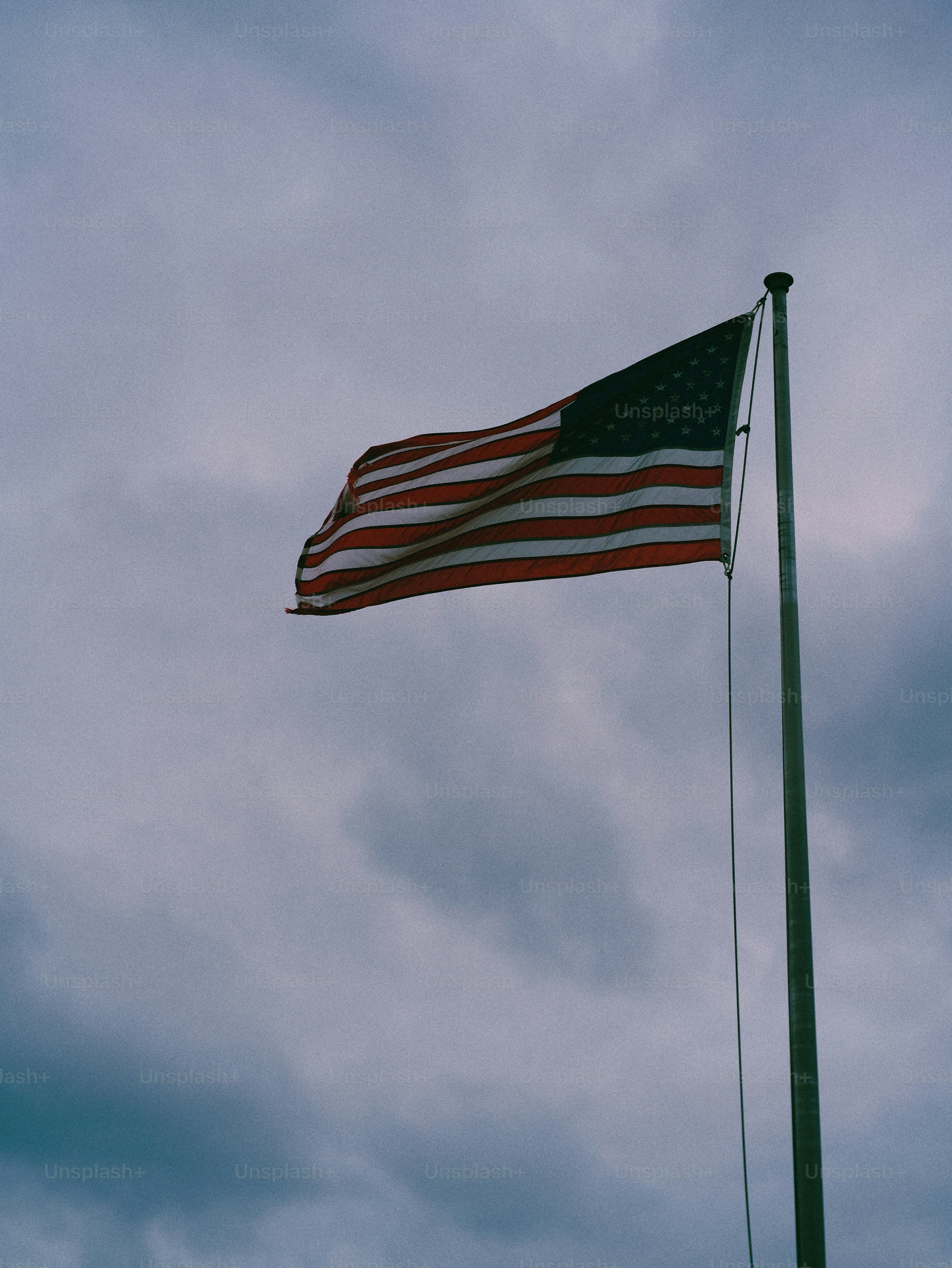 American flag waving on a flagpole against cloudy sky