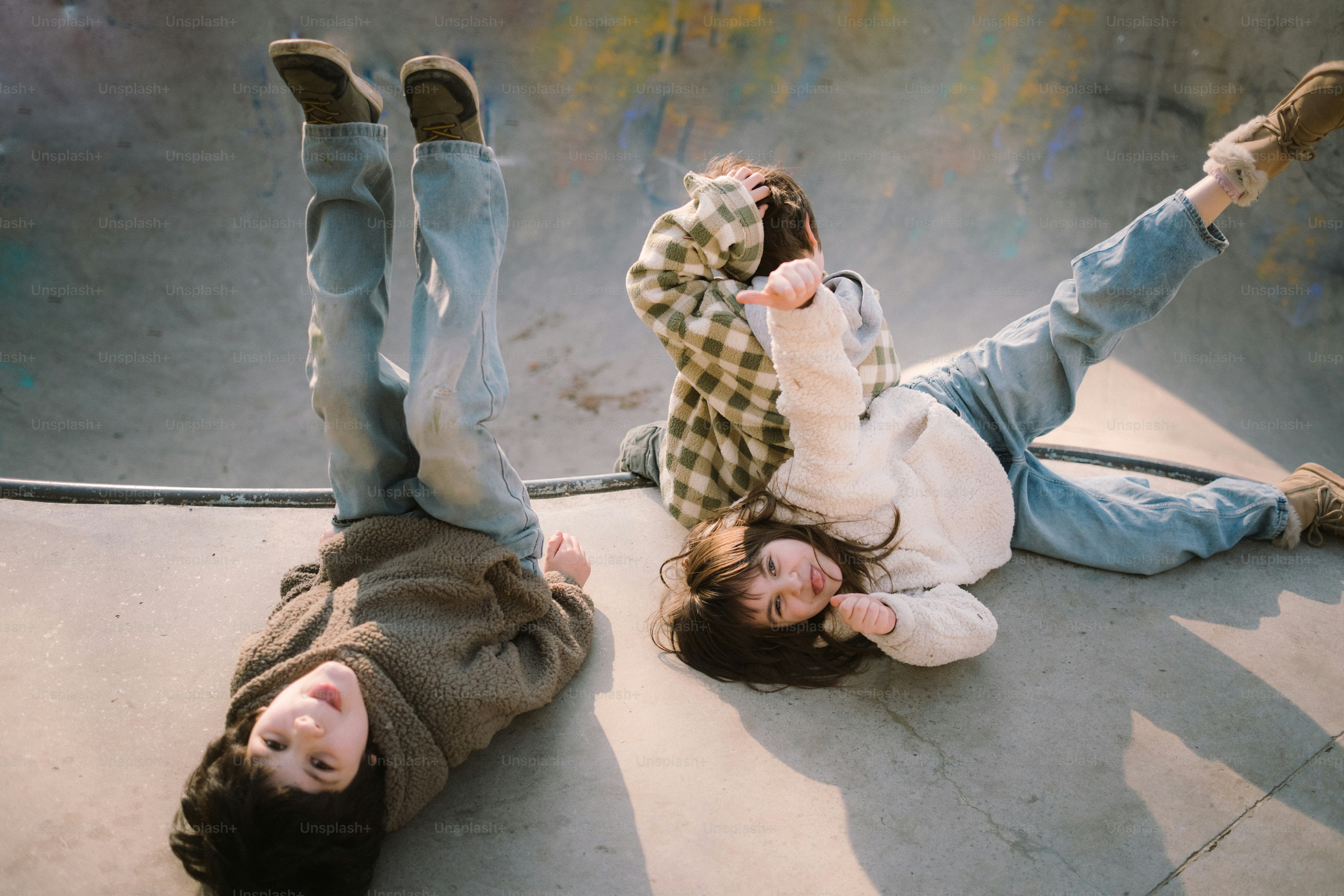Two people lying upside down in a skate park
