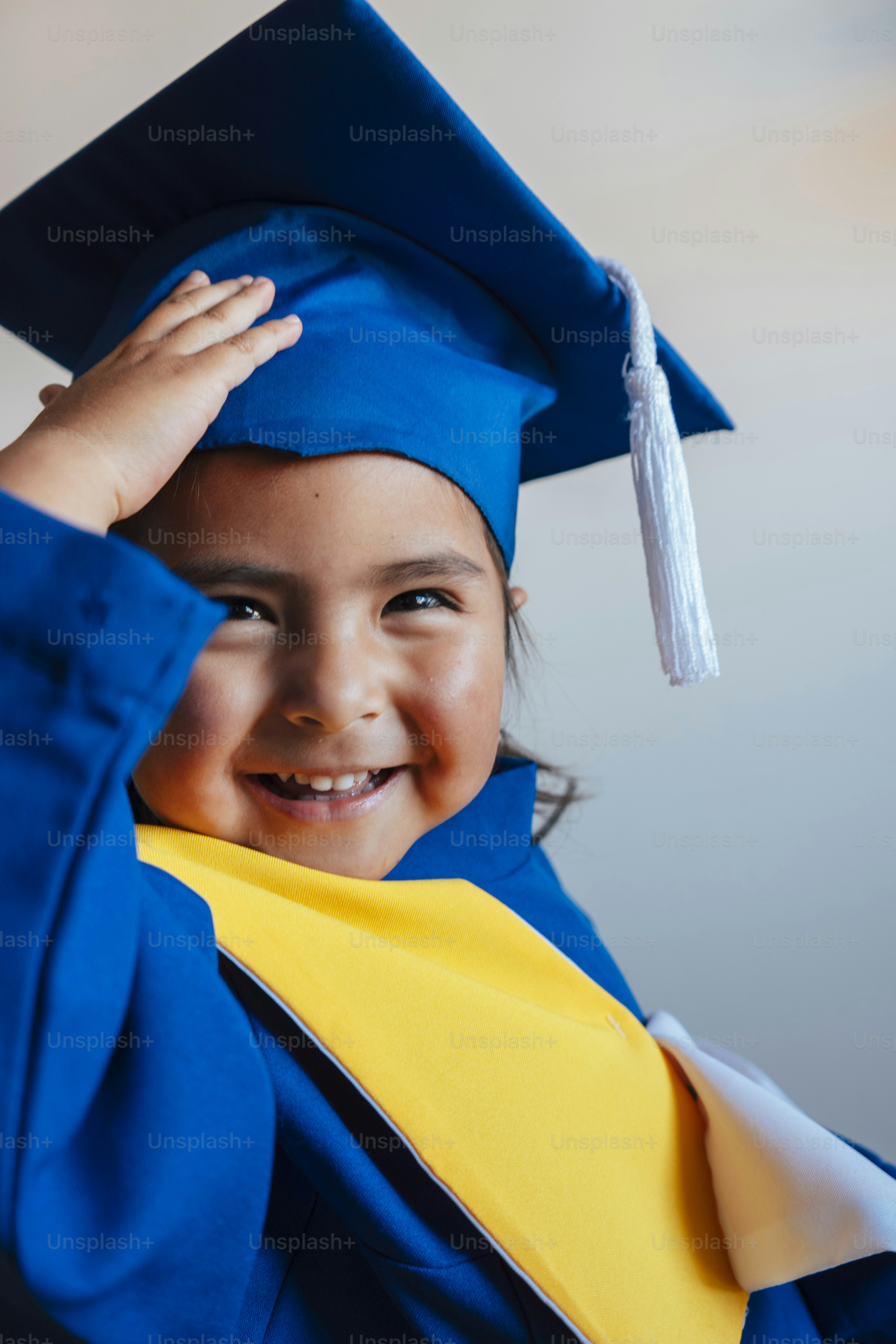 A smiling child in a graduation cap holds a diploma. photo – Education ...