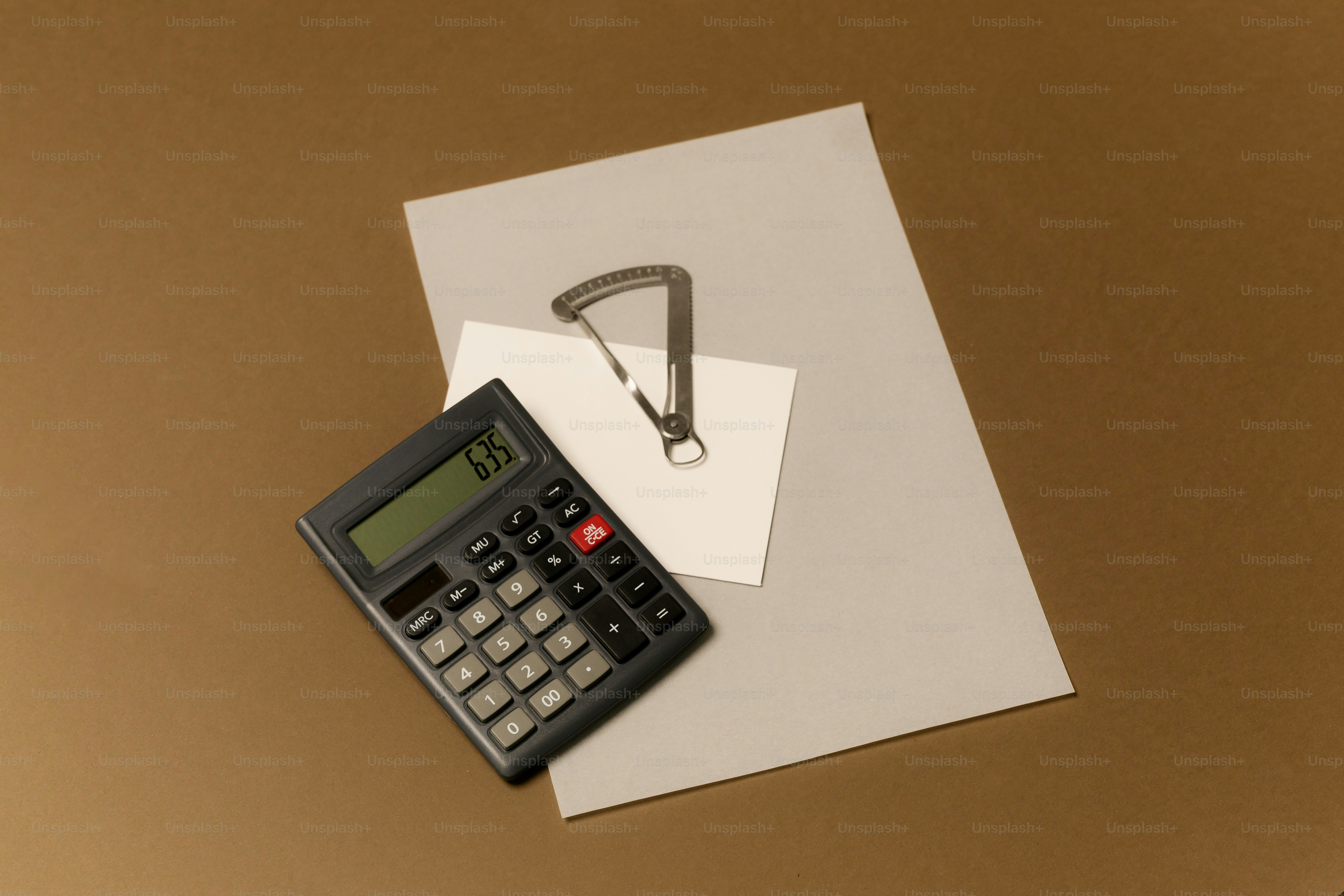Calculator, caliper, and papers on a brown background
