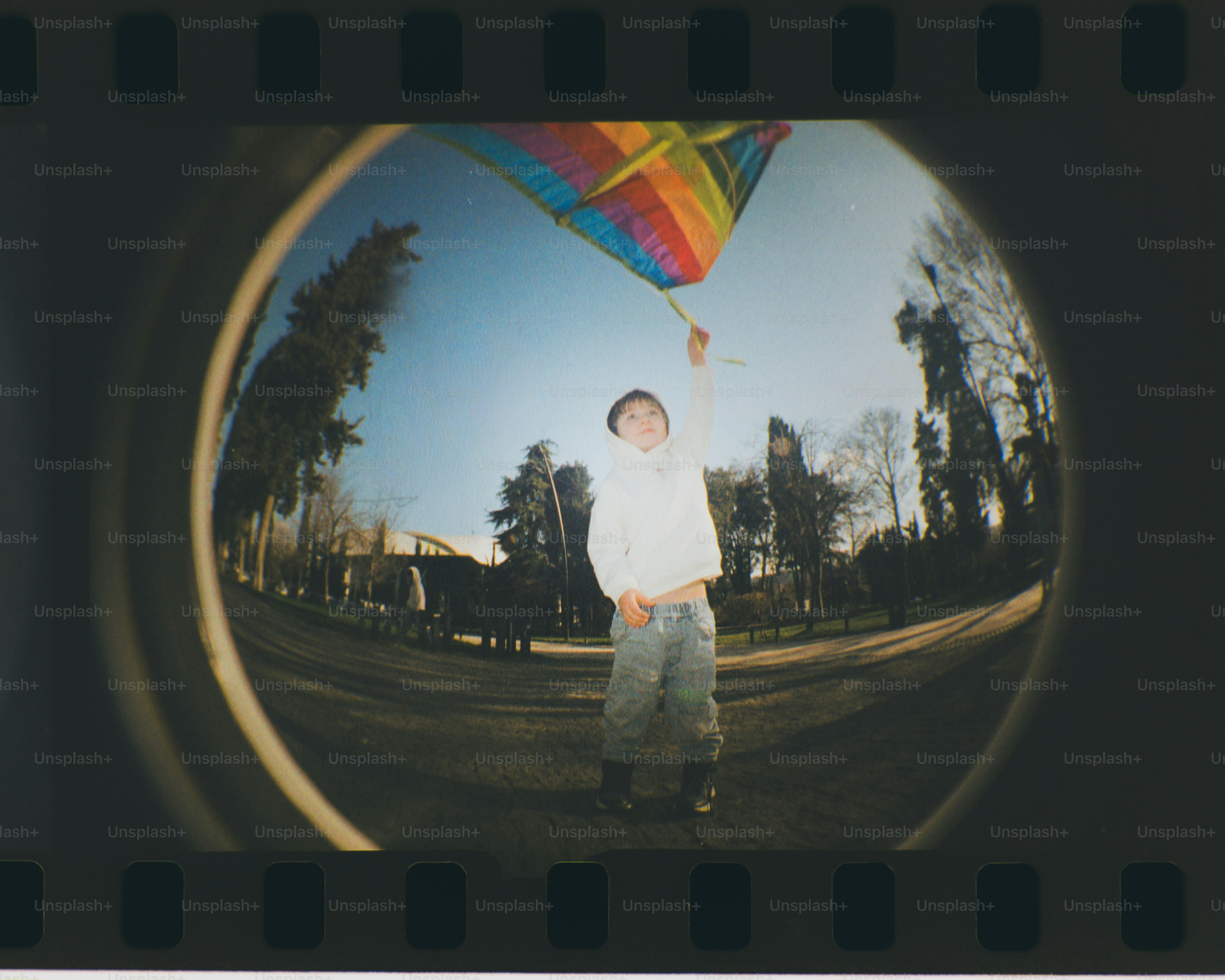 Boy flying a rainbow kite in a park