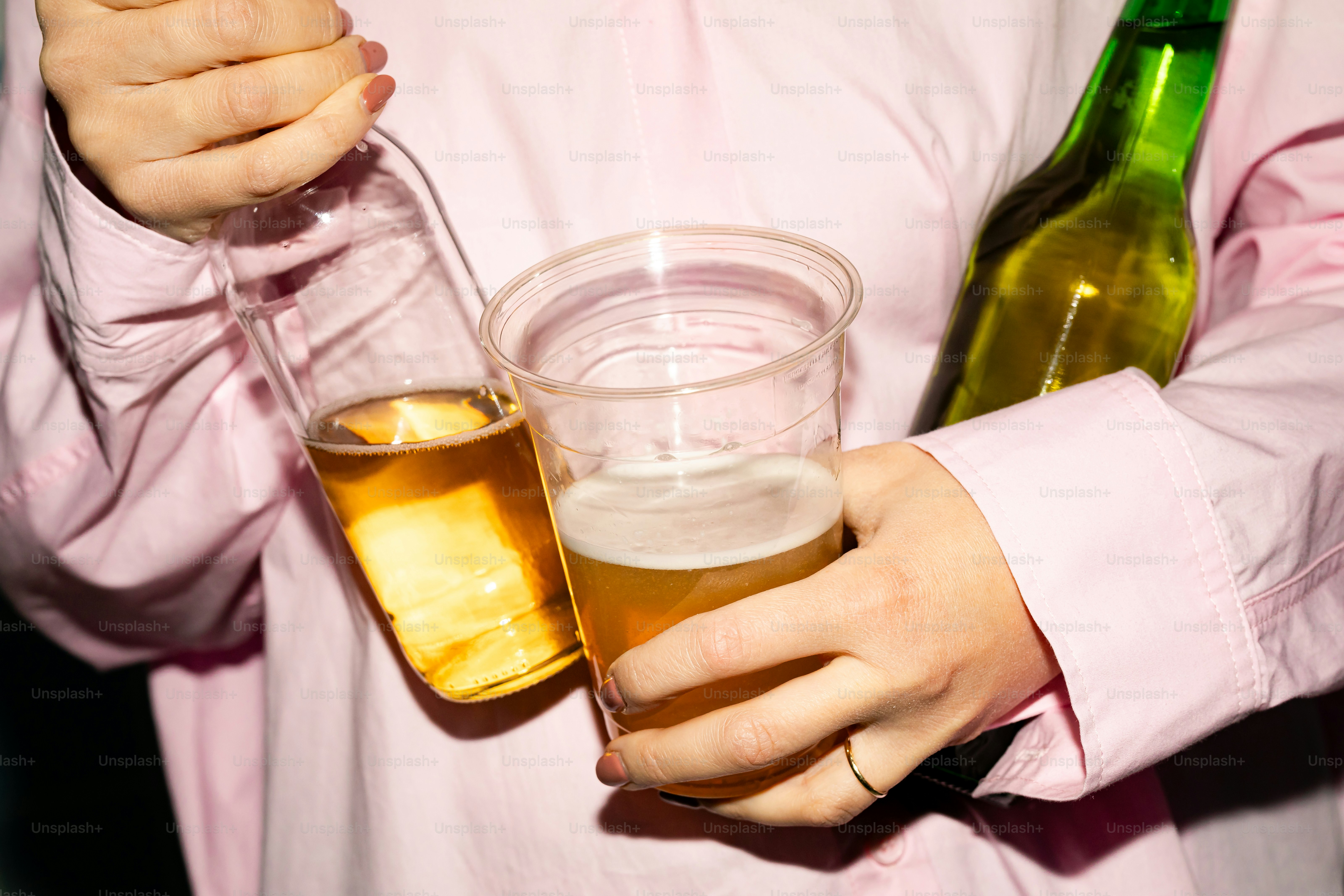 맥주병과 플라스틱 컵을 든 사람.