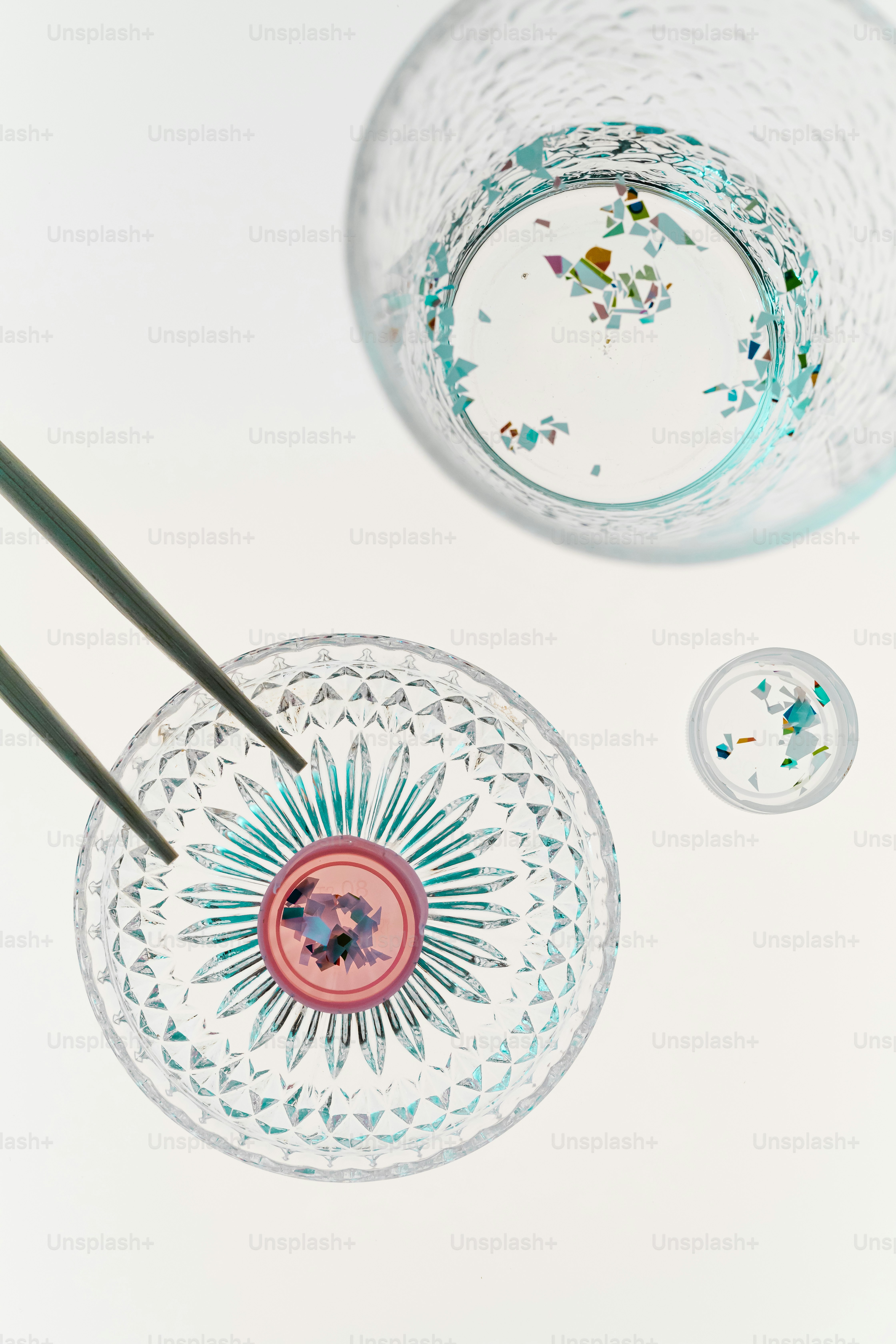 Chopsticks picking up colorful confetti from a glass bowl