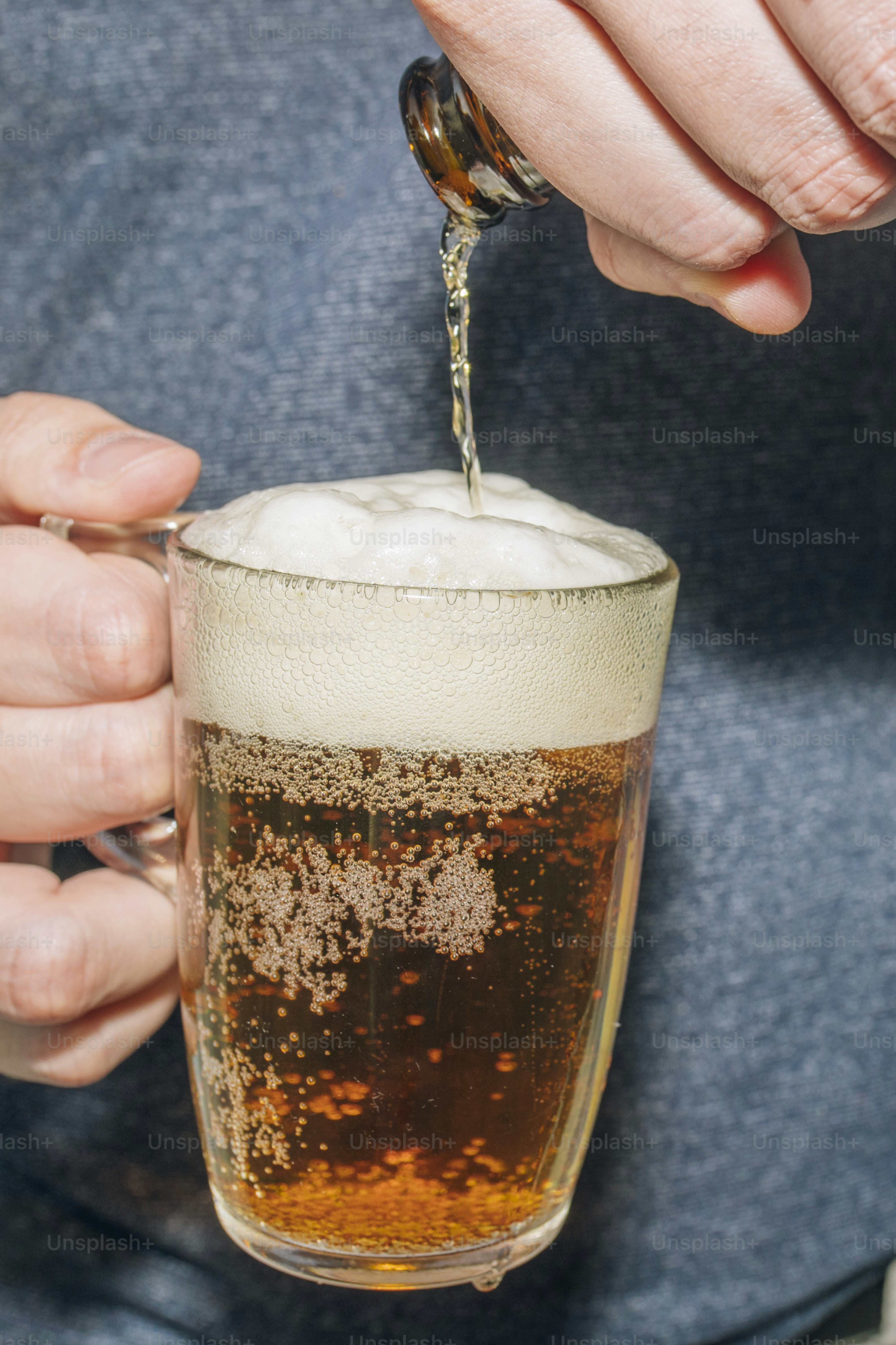 Cerveja sendo servida em uma caneca de vidro com espuma.