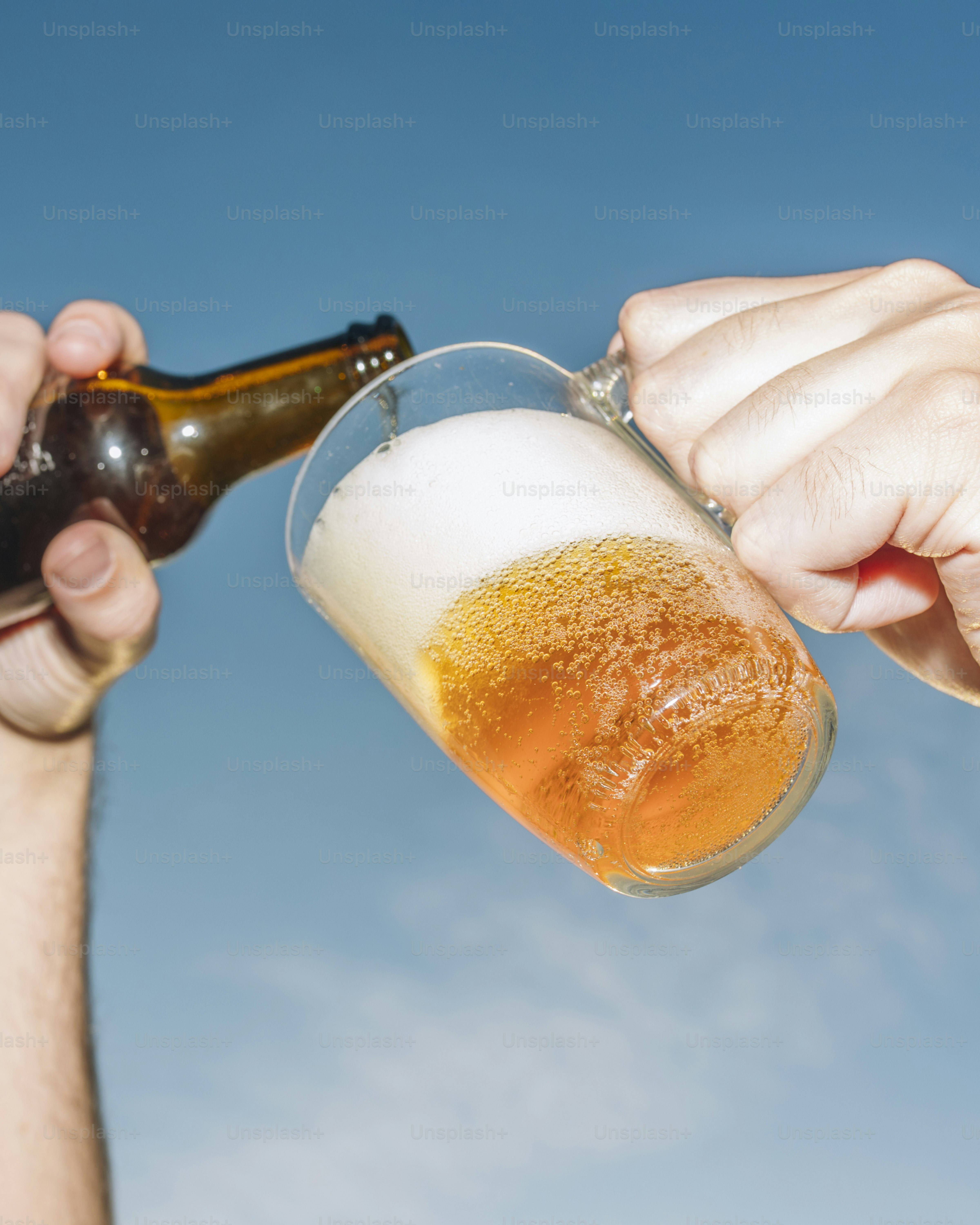 Derramando cerveja em um copo sob um céu azul