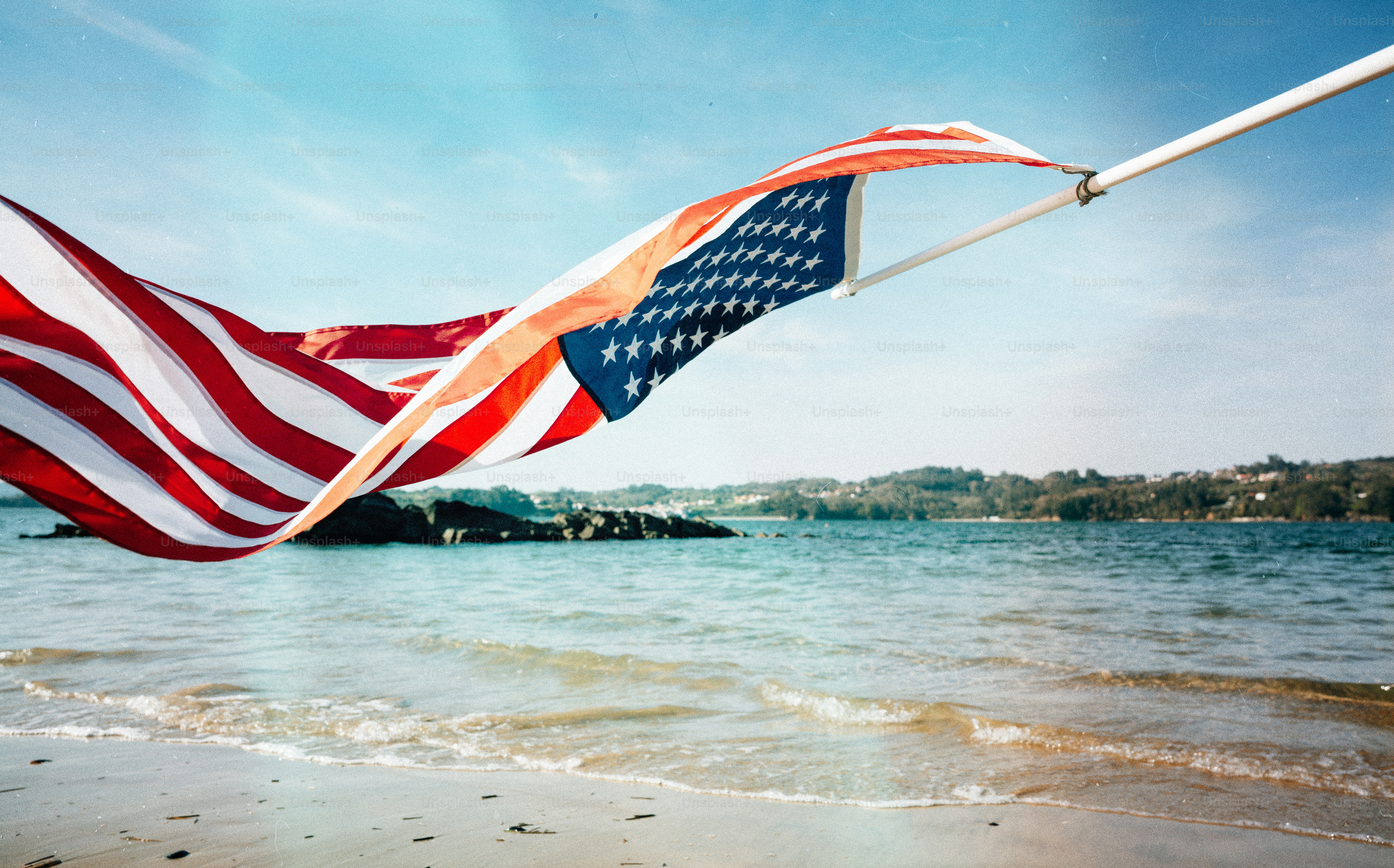 American flag waving on a pole by the sea