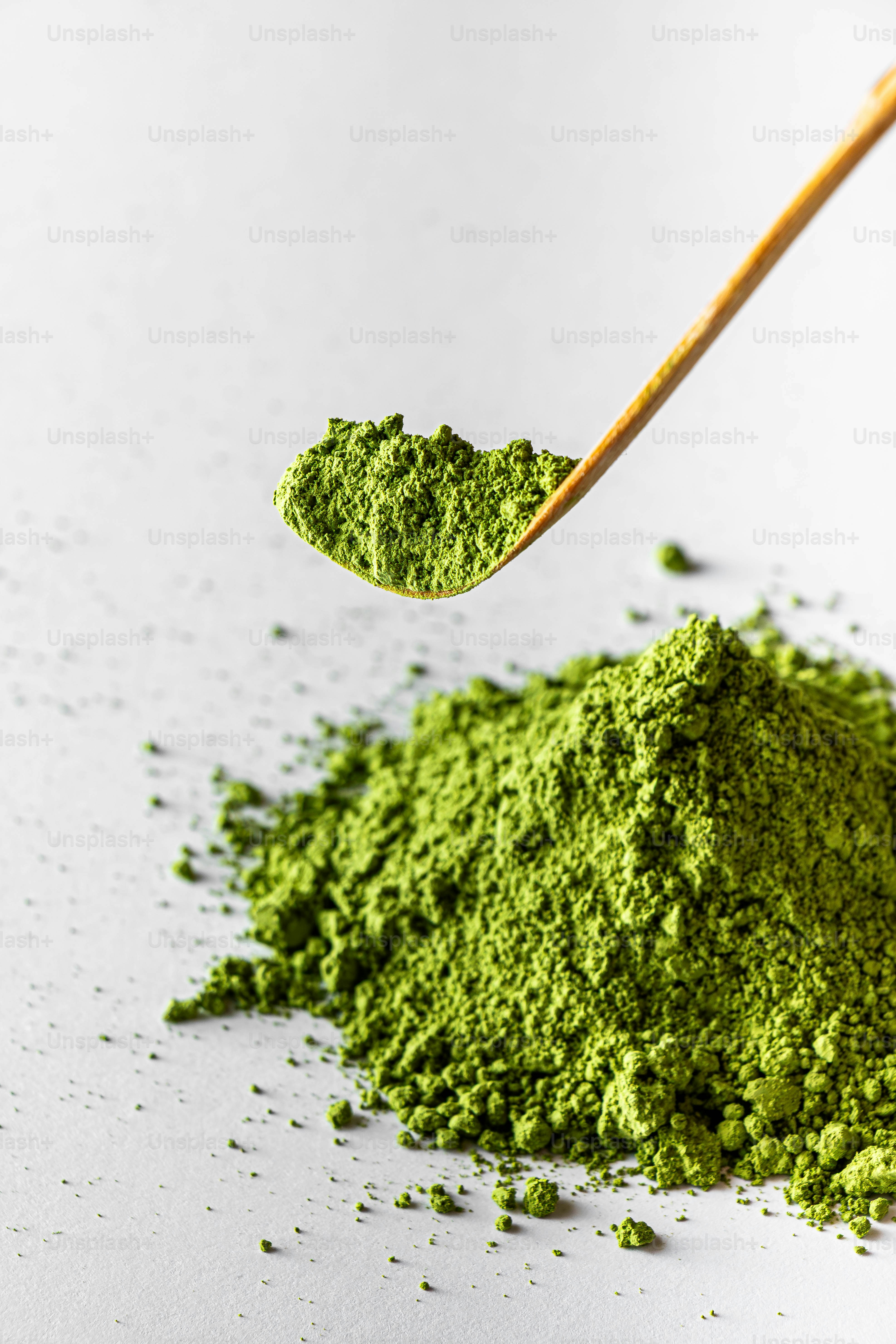 木のスプーンが抹茶粉を山の上に盛っています。